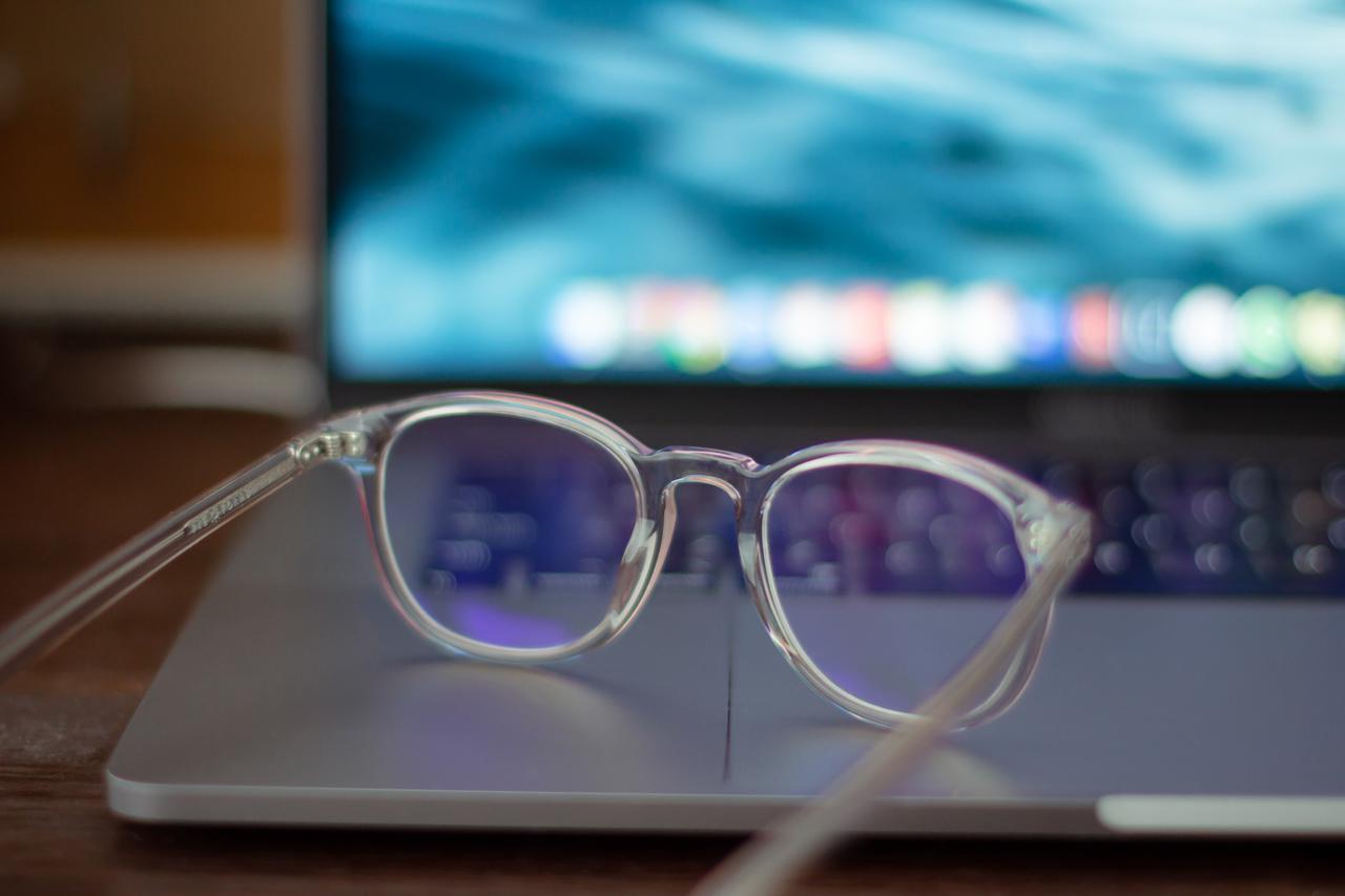 Transparent eyeglasses lying on a laptop.