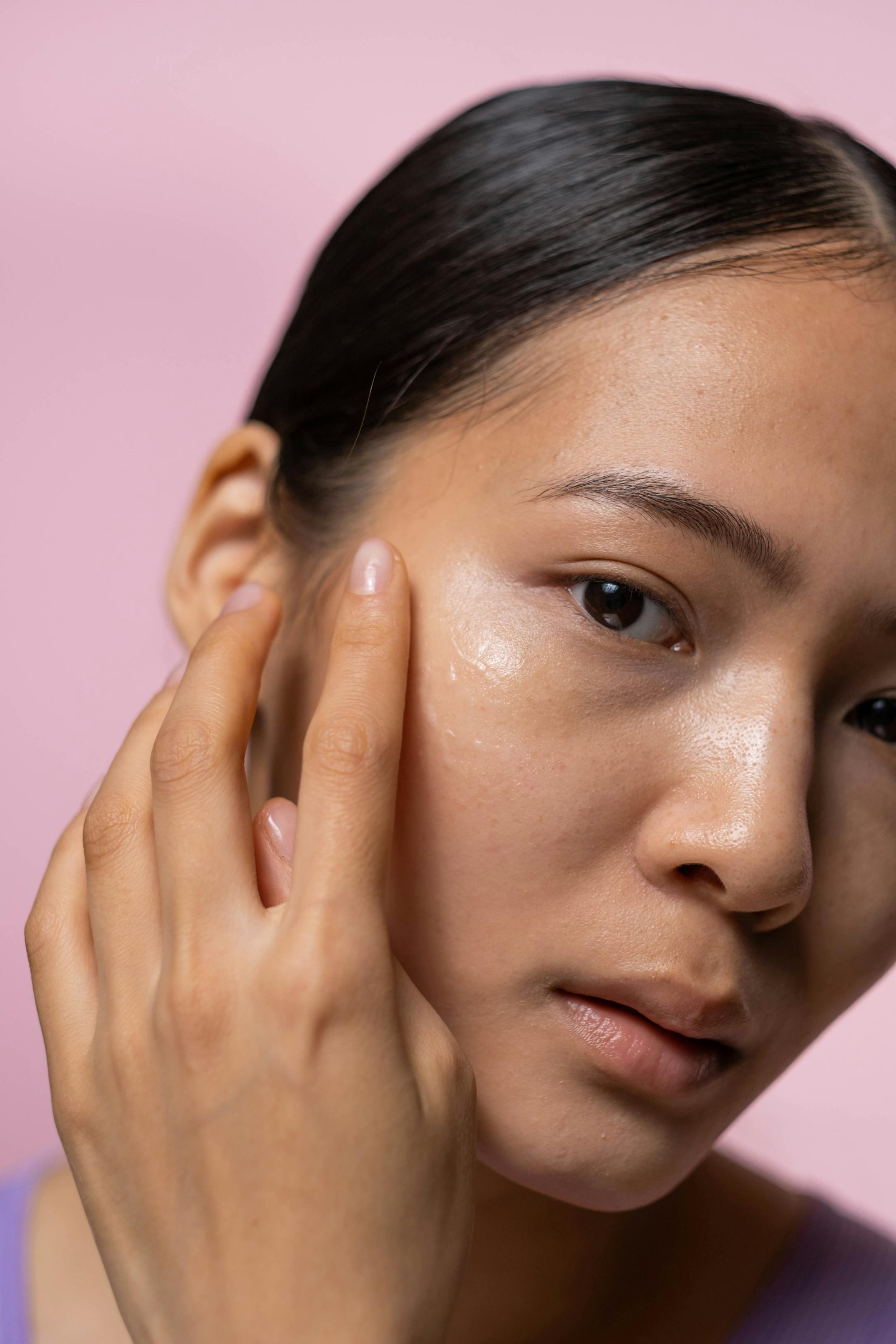 A woman applying facial serum in a studio setting. Perfect for beauty and skincare branding.