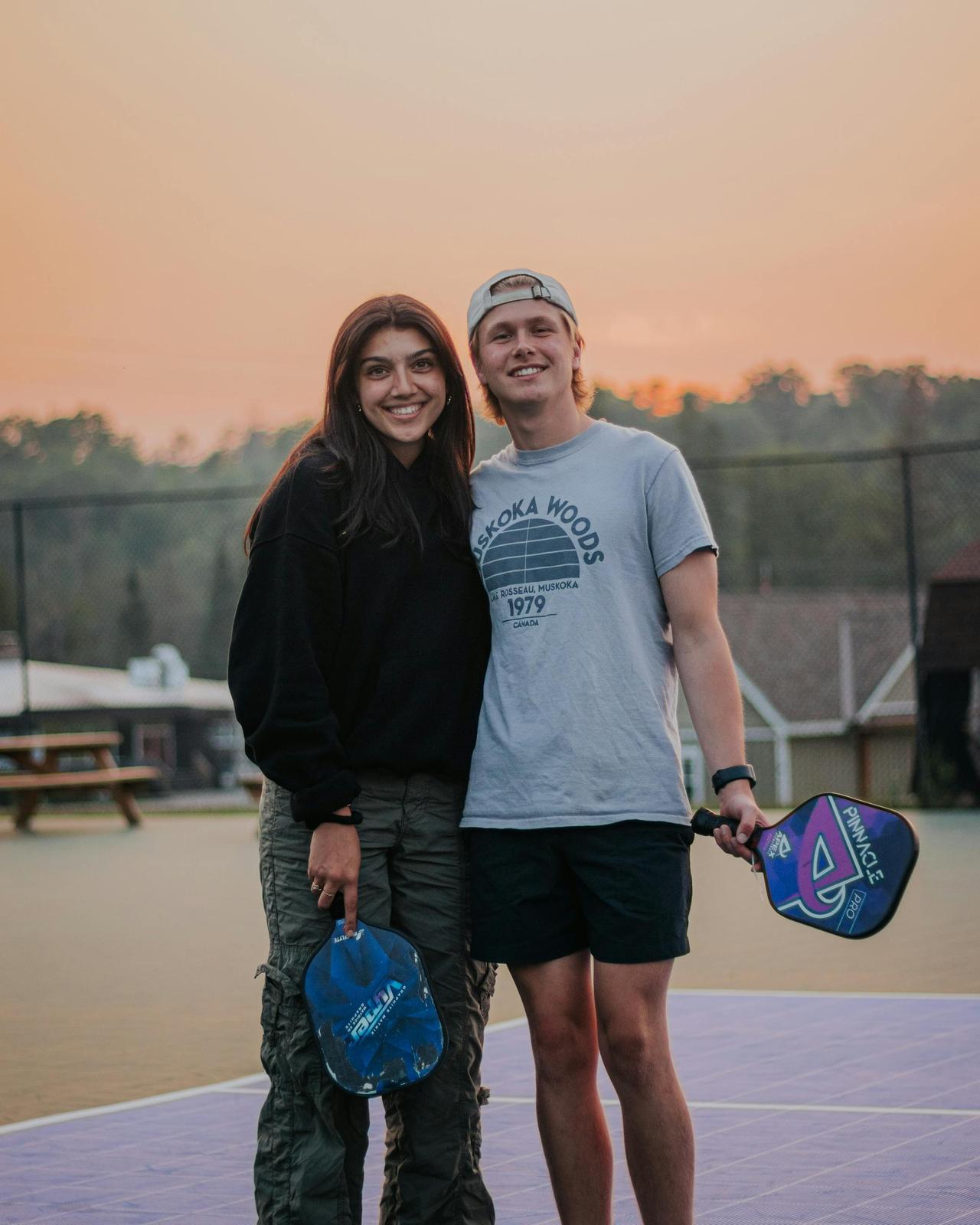 Couple having fun playing pickleball outdoors at sunset.