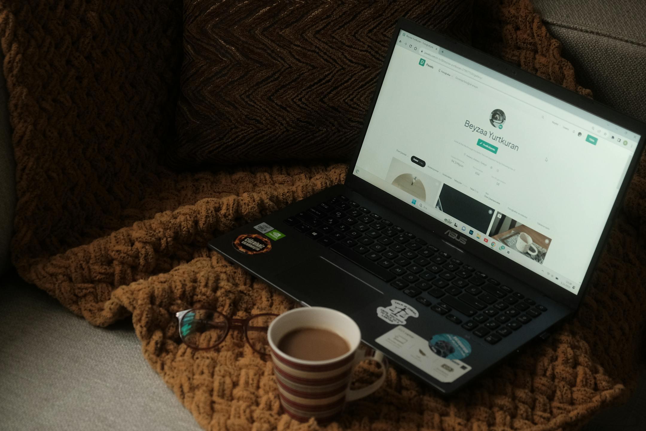A laptop and coffee mug on a cozy couch setting, perfect for relaxed work or browsing.