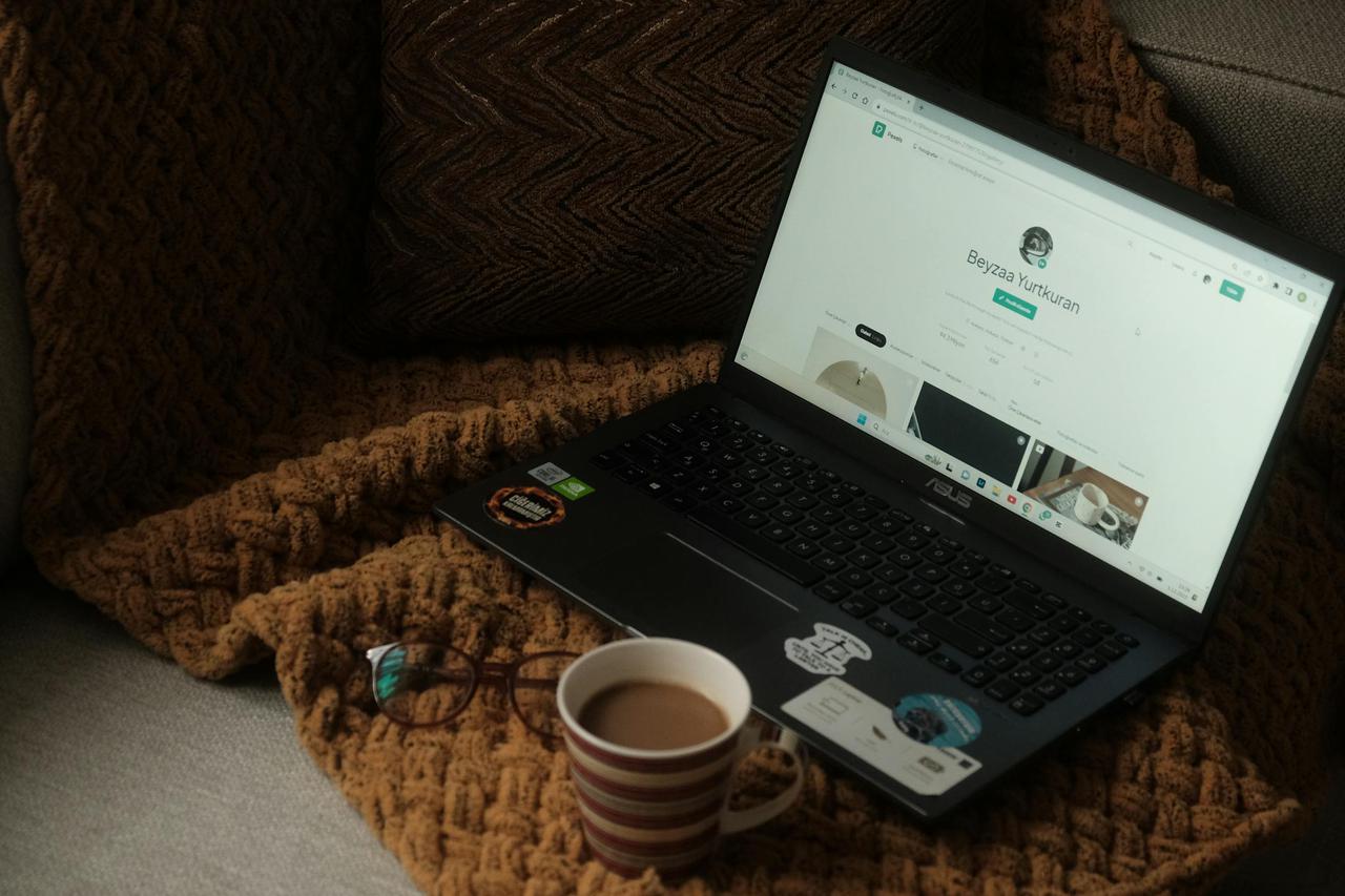 A laptop and coffee mug on a cozy couch setting, perfect for relaxed work or browsing.