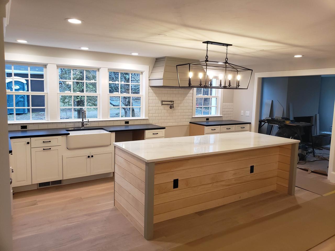 kitchen-with-four-windows-with-white-tile-white cabinets-and-wood-cabinet-island
