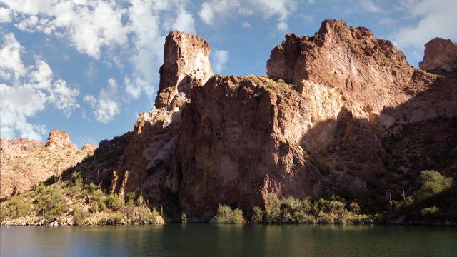 Scenic view of rugged cliffs and tranquil water in Apache Junction, Arizona under a bright blue sky.