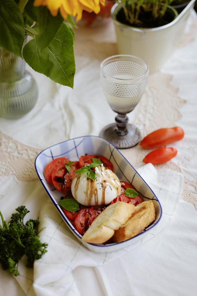 Fresh Caprese salad with burrata cheese and tomatoes, beautifully styled on a lace tablecloth.