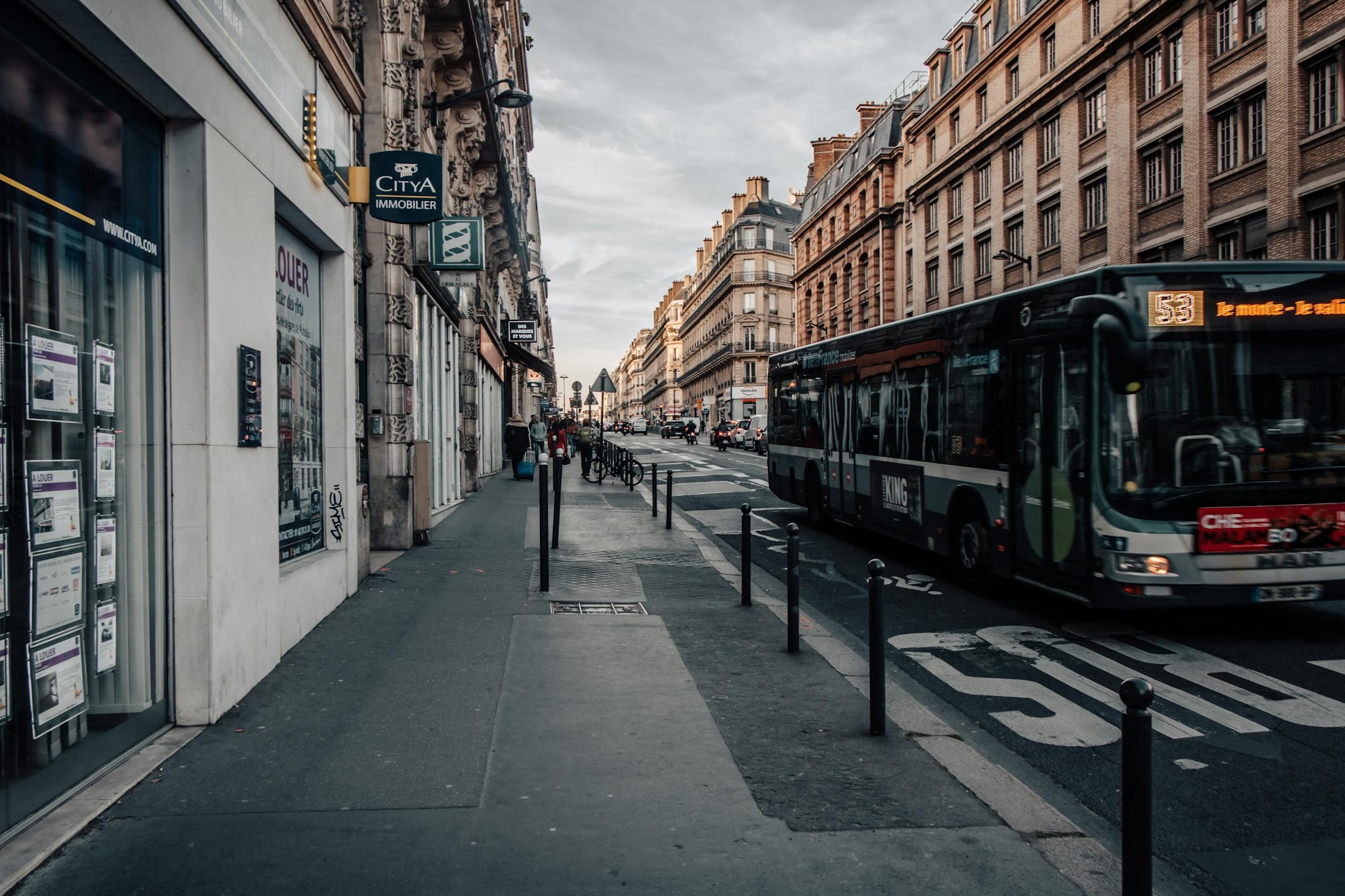 A bustling Paris street scene with a bus, historic buildings, and a quiet sidewalk atmosphere.