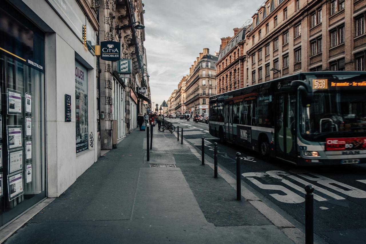 A bustling Paris street scene with a bus, historic buildings, and a quiet sidewalk atmosphere.