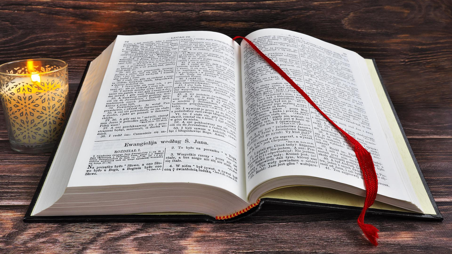 An open bible with red bookmark across the page