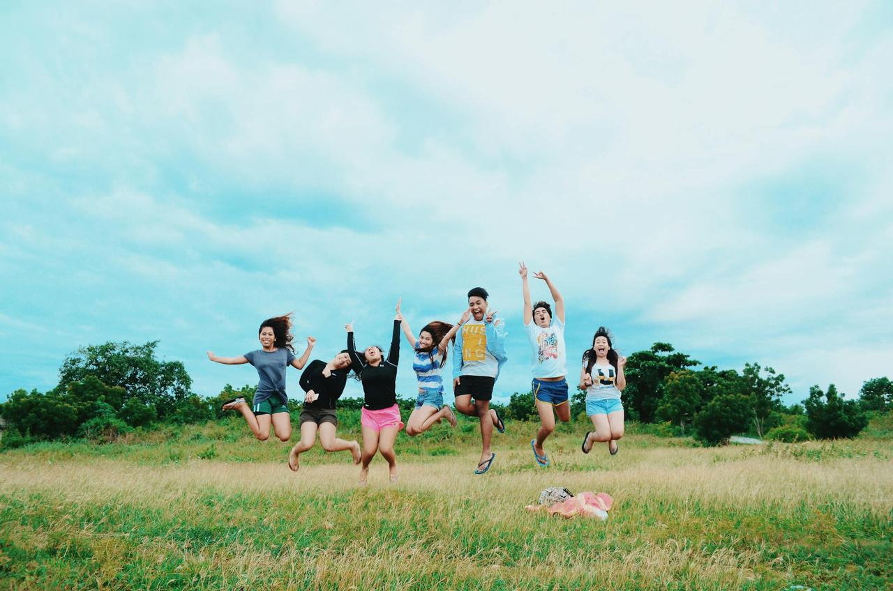 A lively group of friends enjoying a jump shot in a sunny outdoor setting.