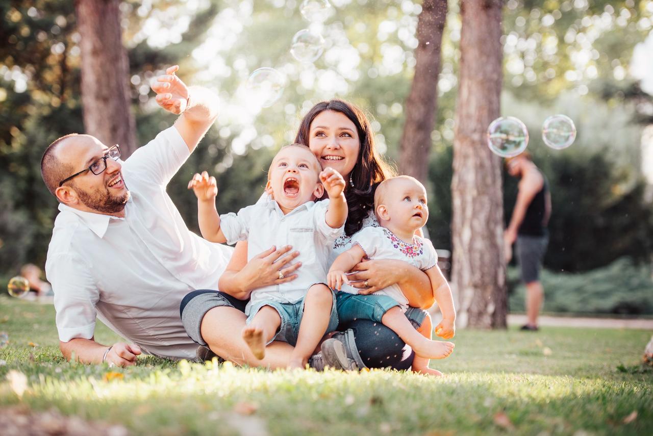 Joyful family enjoying a sunny day in the park while playing with bubbles.