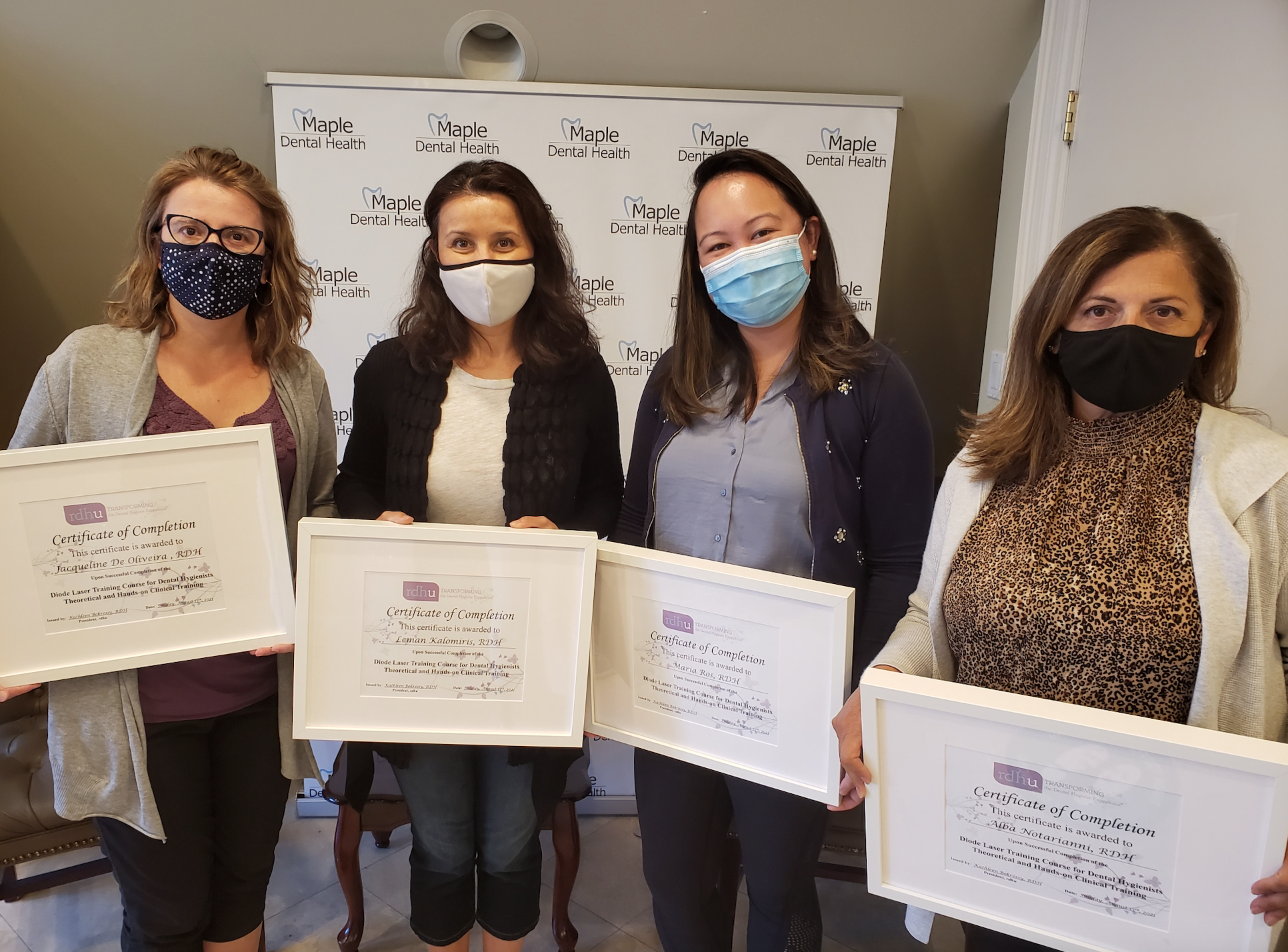 Healthcare workers holding up their dental hygiene laser certificates.