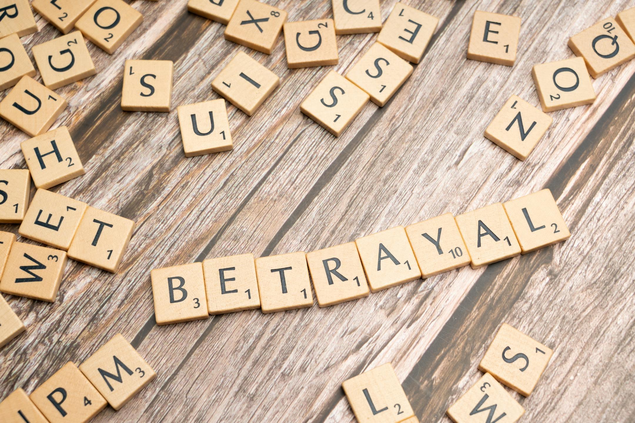 Wooden letter tiles spelling 'Betrayal' on a rustic wooden surface, conveying themes of deceit and dishonesty.