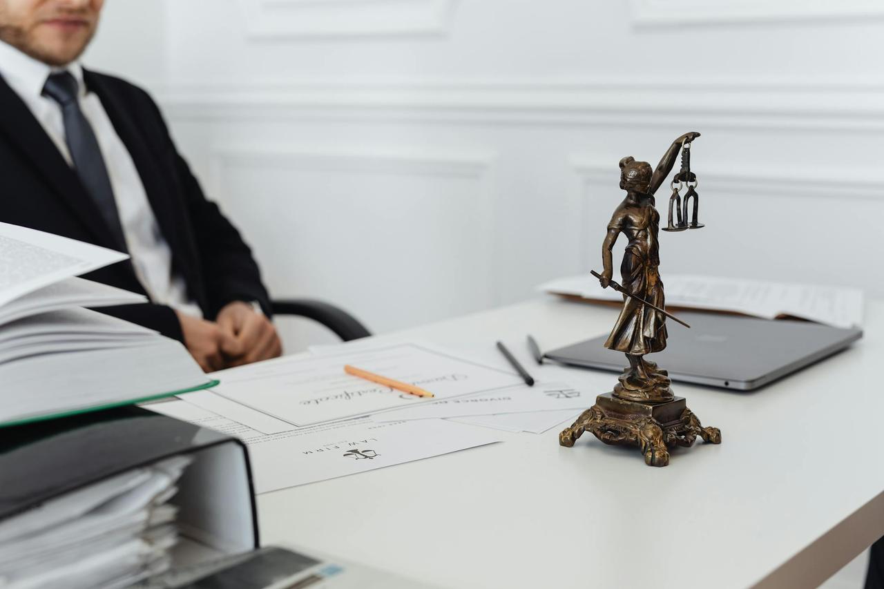 A legal professional's workspace featuring Lady Justice statue, documents, and a laptop.