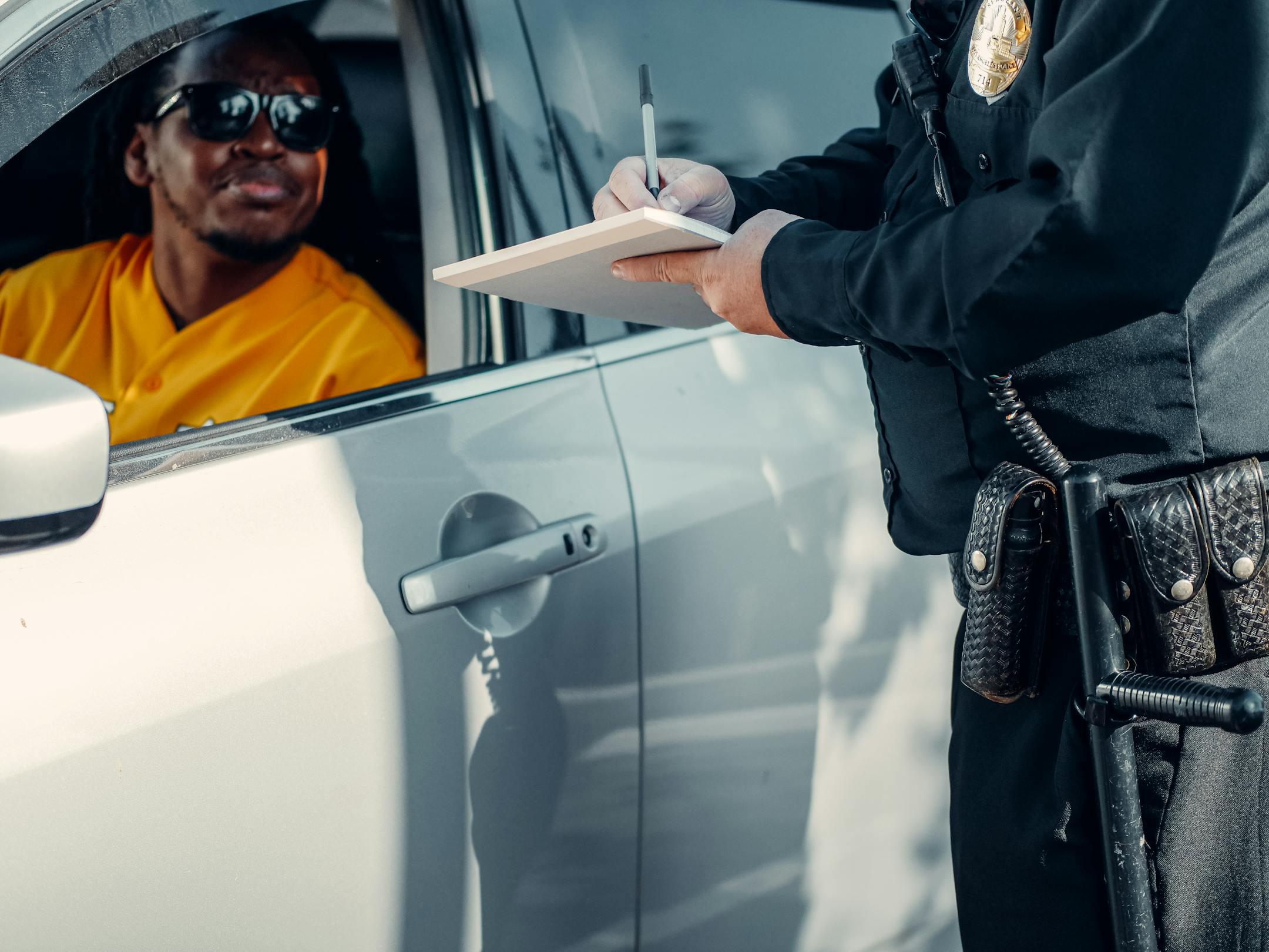 A police officer writes a ticket for a driver in need of a good ticket attorney