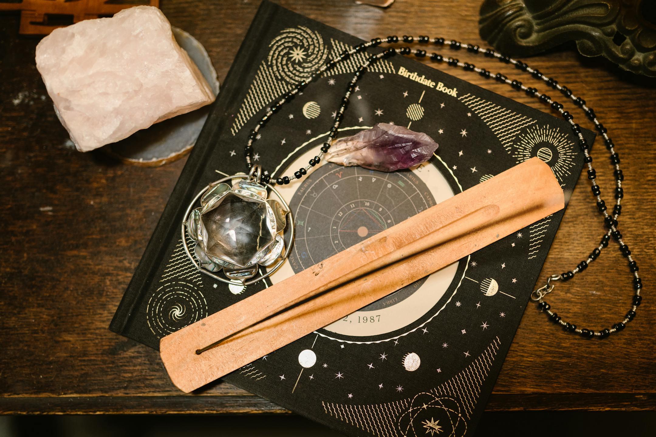 Top view of an astrology book, crystals, and incense holder for mystical ambiance.