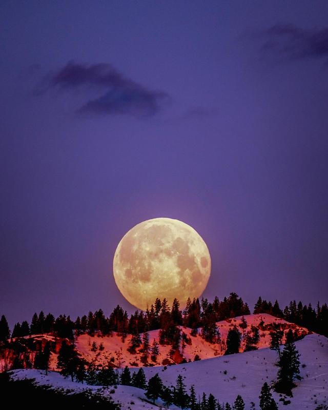 A breathtaking supermoon illuminating snow-covered hills under a purple sky in Wenatchee, WA.