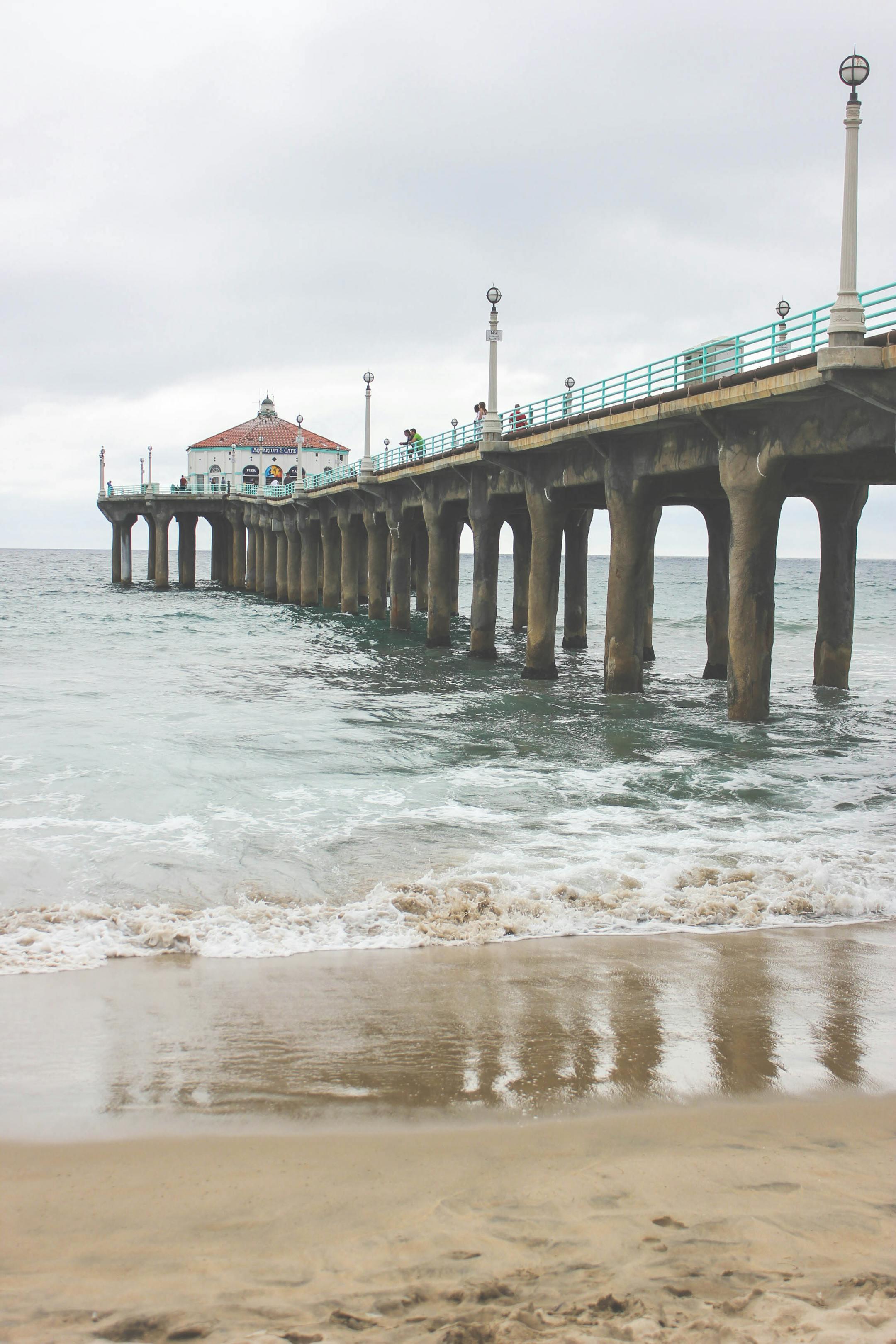 A tranquil view of an iconic pier extending into the sea, under an overcast sky.