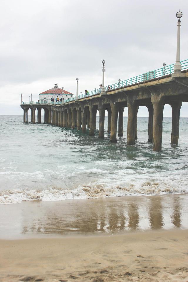 A tranquil view of an iconic pier extending into the sea, under an overcast sky.