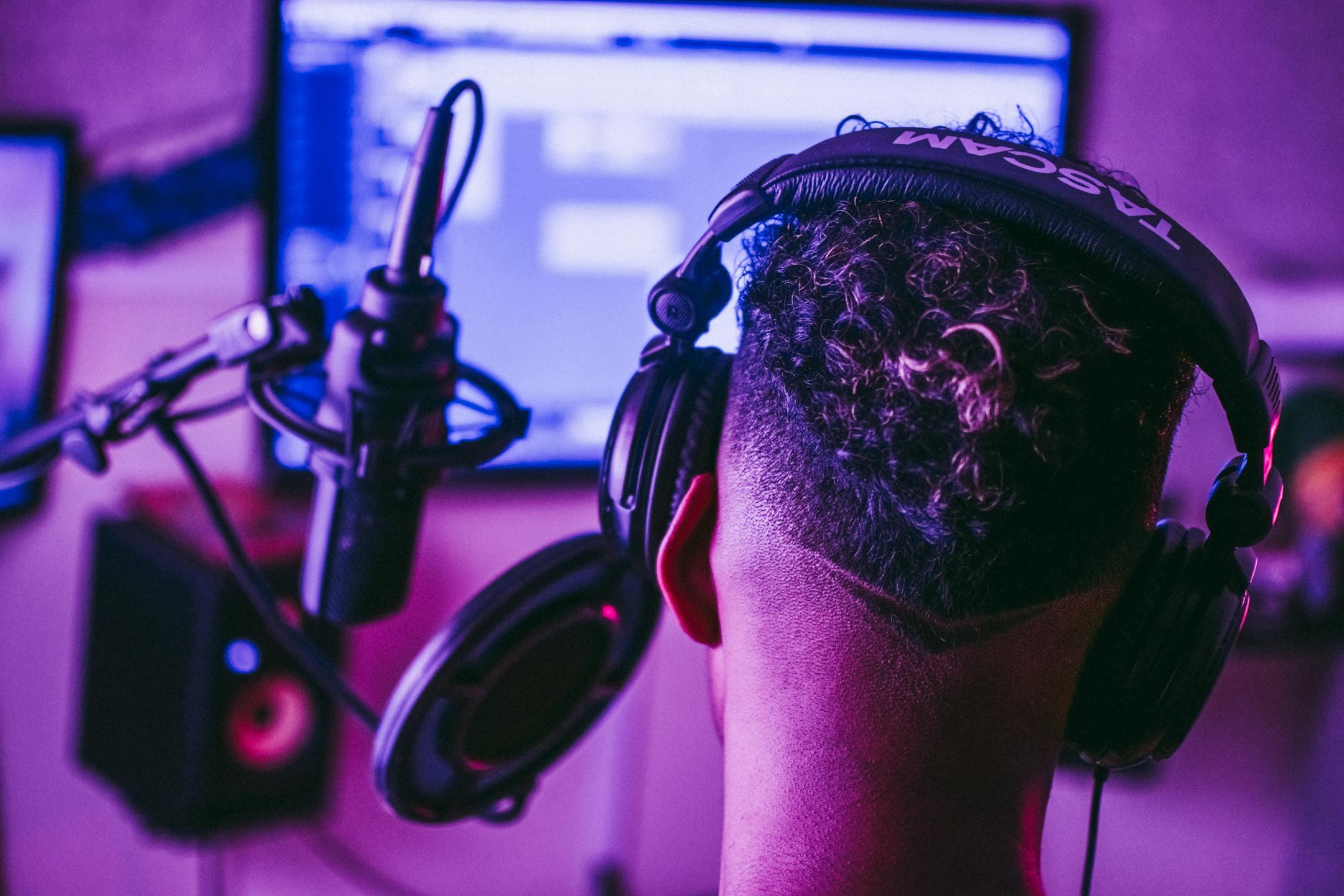 Back view of a music producer working in a vibrant recording studio setting.
