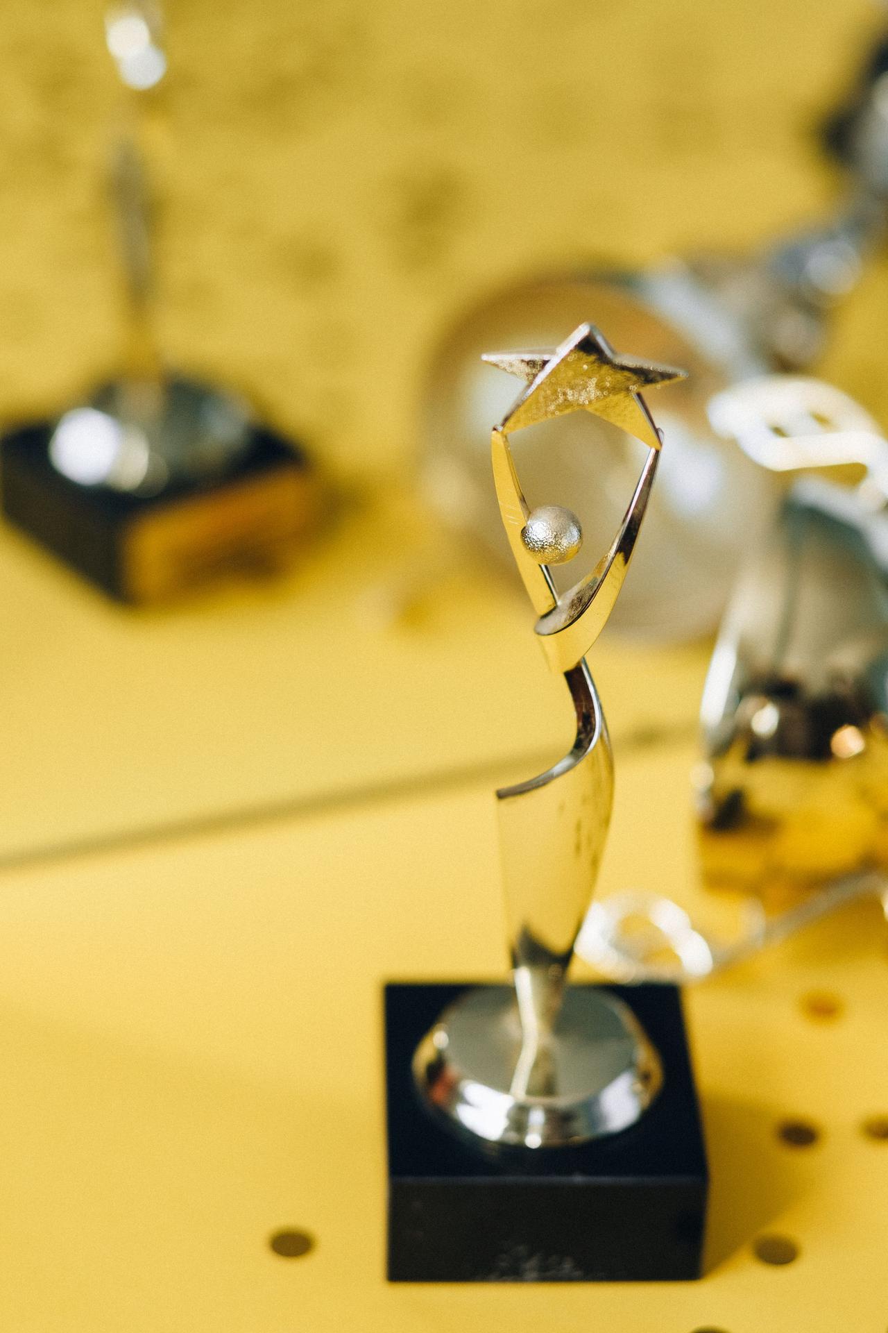 Close-up of a stylish silver trophy on a golden reflective surface.