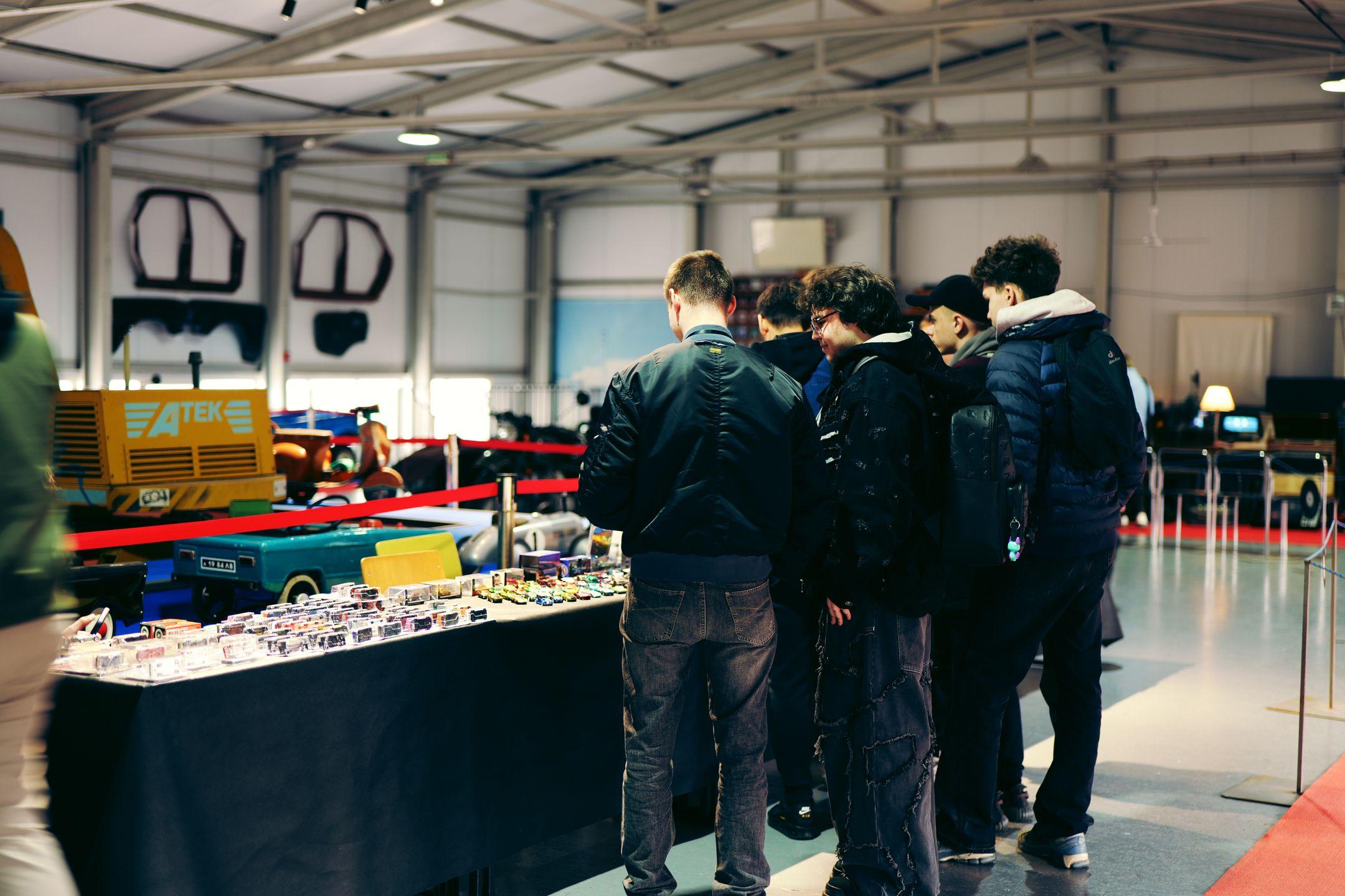 Attendees explore mini car models at an indoor automotive exhibition.