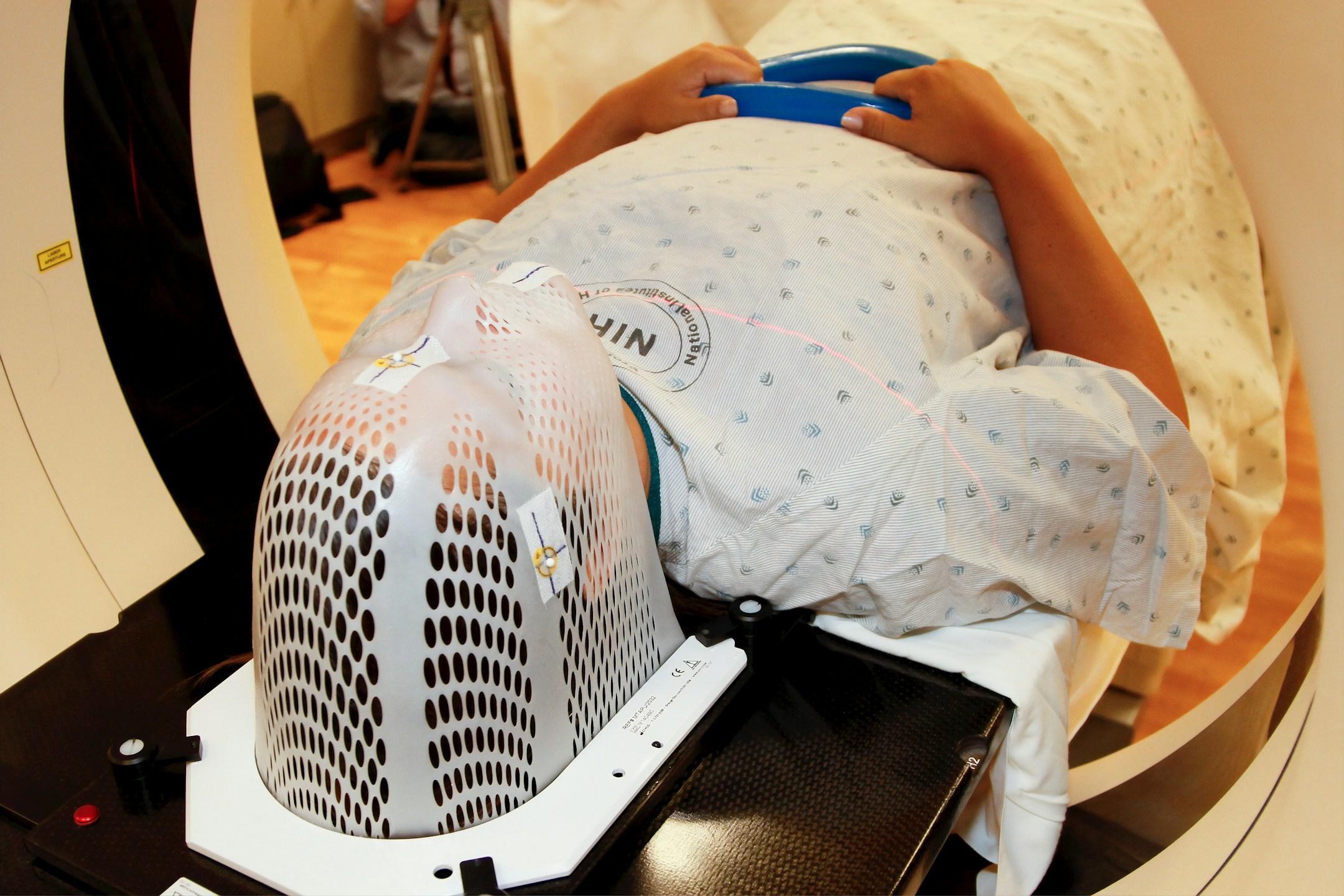 A patient model wearing a short face mask is positioned in a computed tomography (CT) scanner to obtain images of a tumor before radiation therapy. 2010

