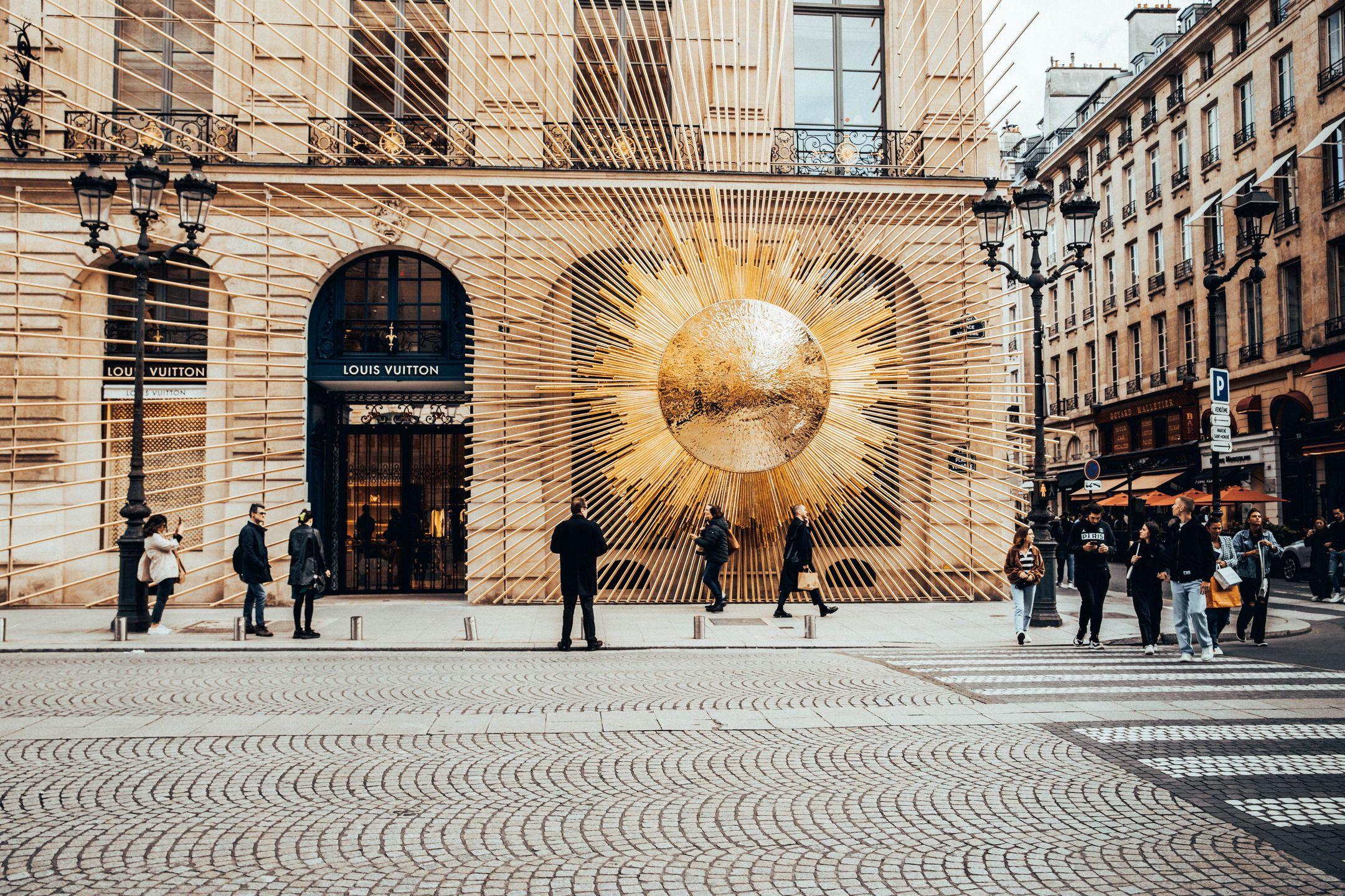 Elegant Louis Vuitton facade in bustling Paris street, showcasing modern artistic design.