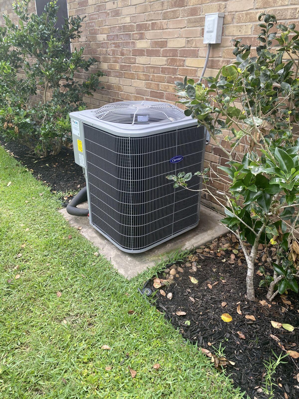 New Carrier air conditioner condenser installed beside a brick home in Spring, TX by AC Repair Expo Heating & Cooling