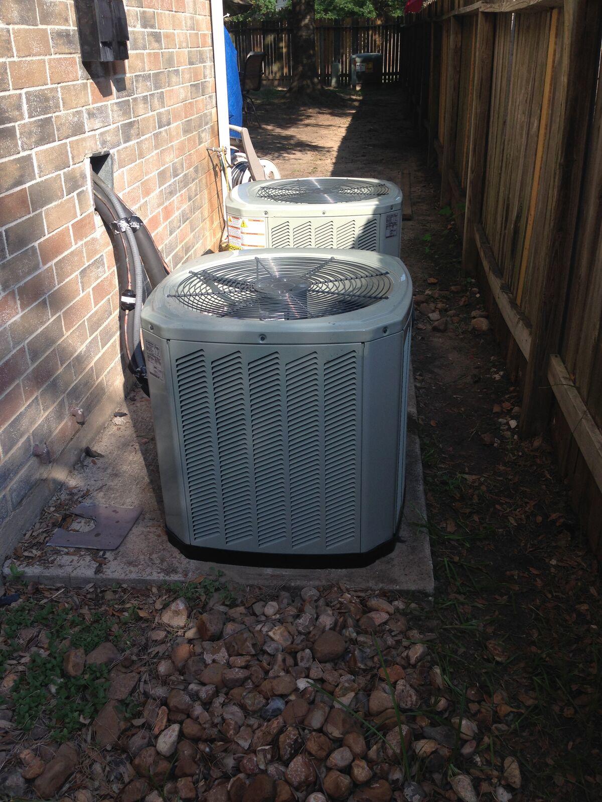 Two Trane AC condensers installed in a narrow side yard in Spring, TX