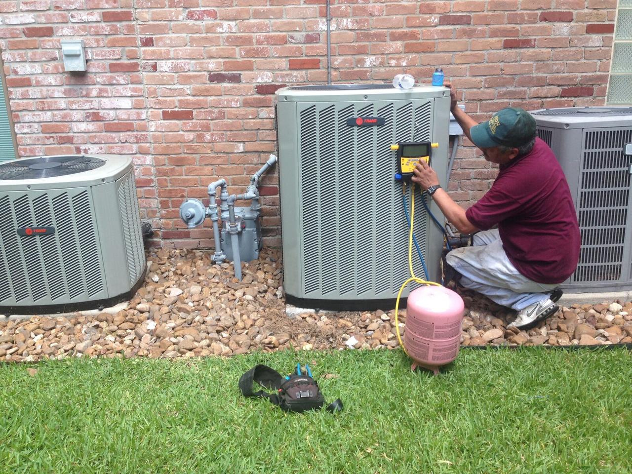 AC Repair Expo technician checking refrigerant charge with digital gauges on a Trane condenser in Spring, TX