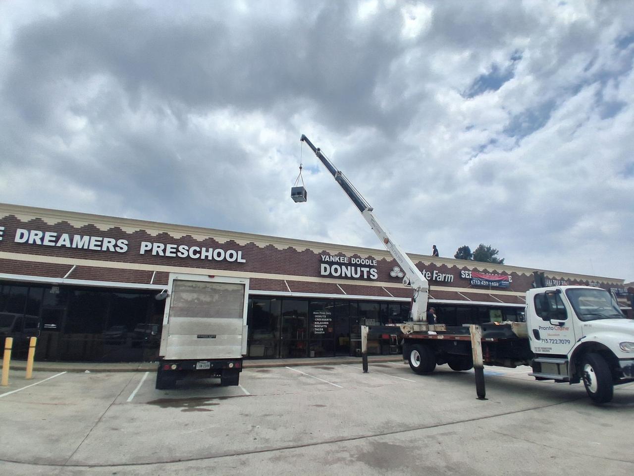 Commercial rooftop package unit lifted by crane for installation in North Houston by AC Repair Expo