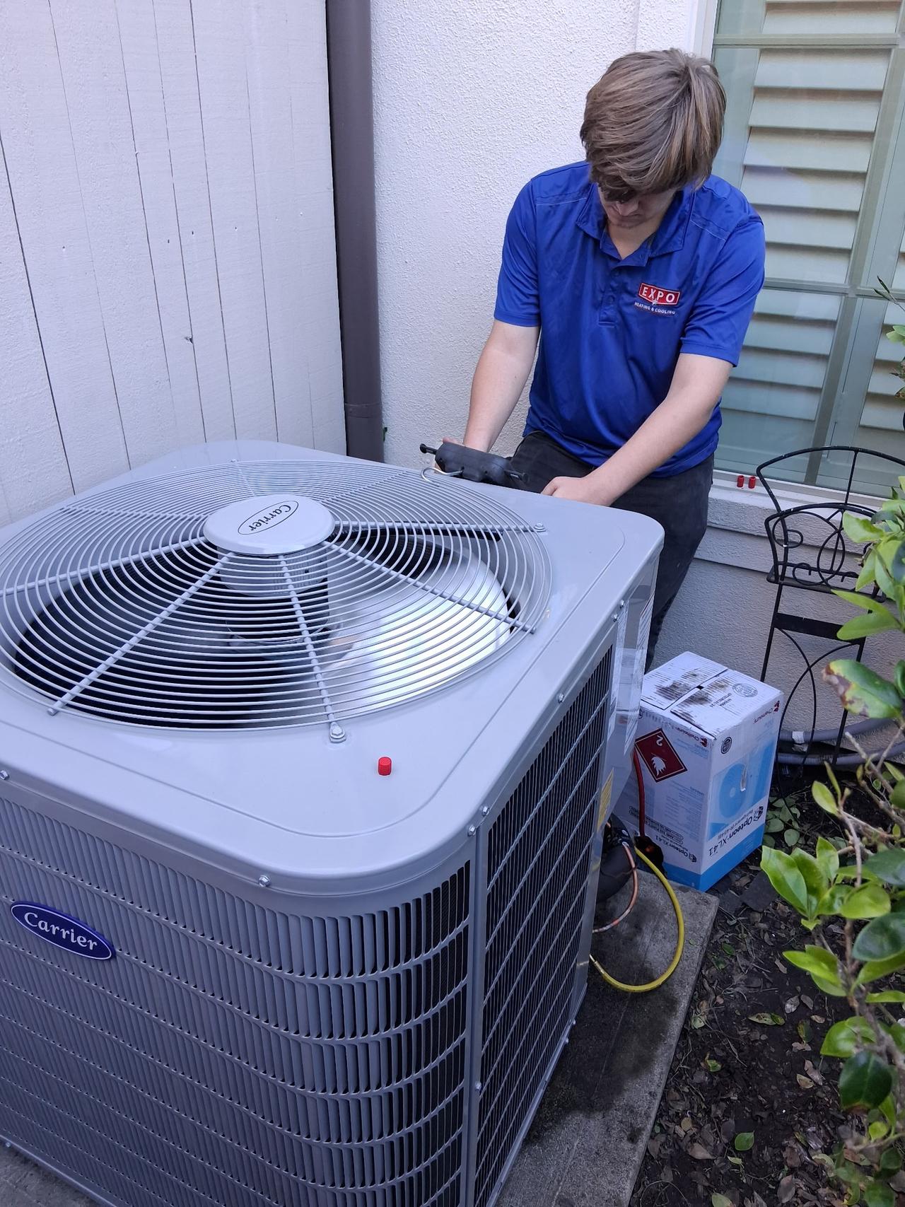 Technician servicing a Carrier Performance 18 two-stage condenser
