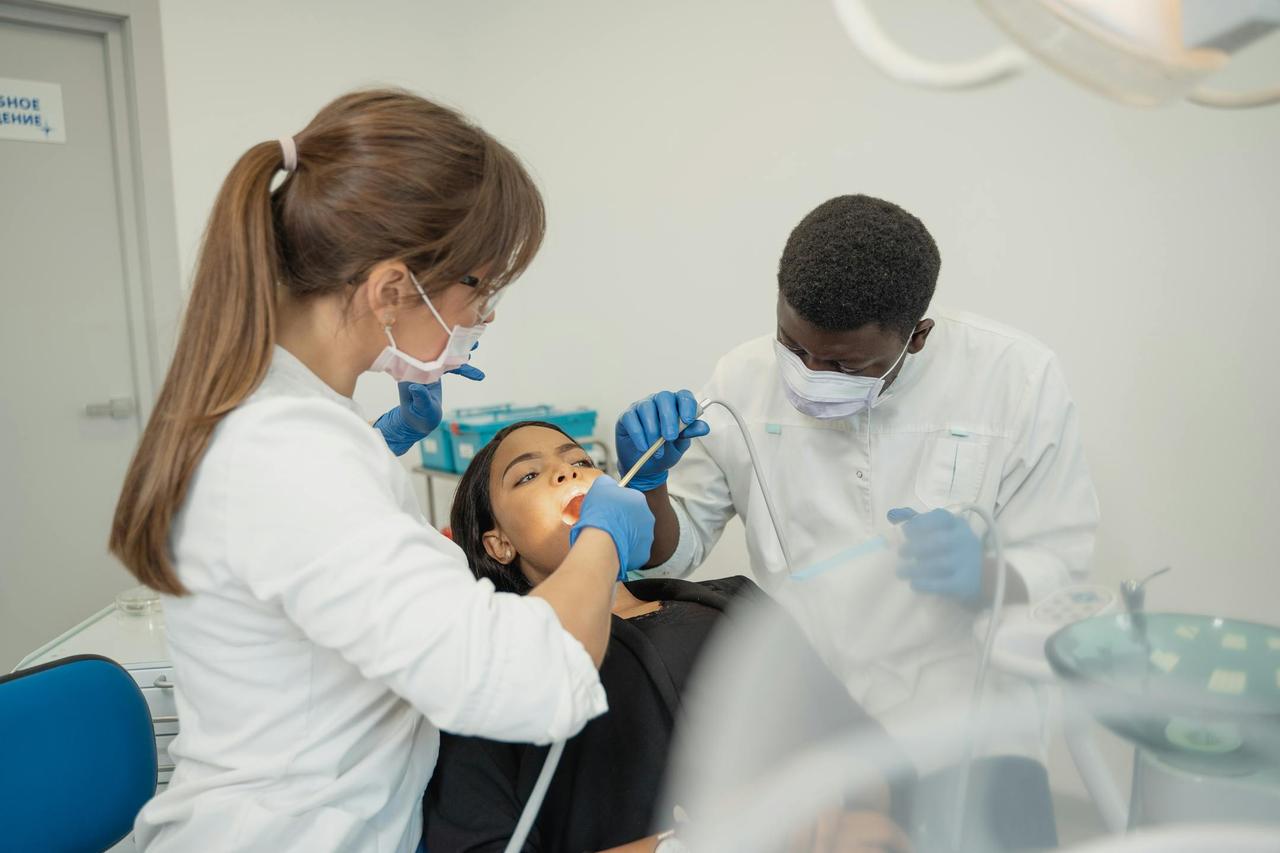 Dentists performing a dental checkup on a patient in a dental clinic setting.