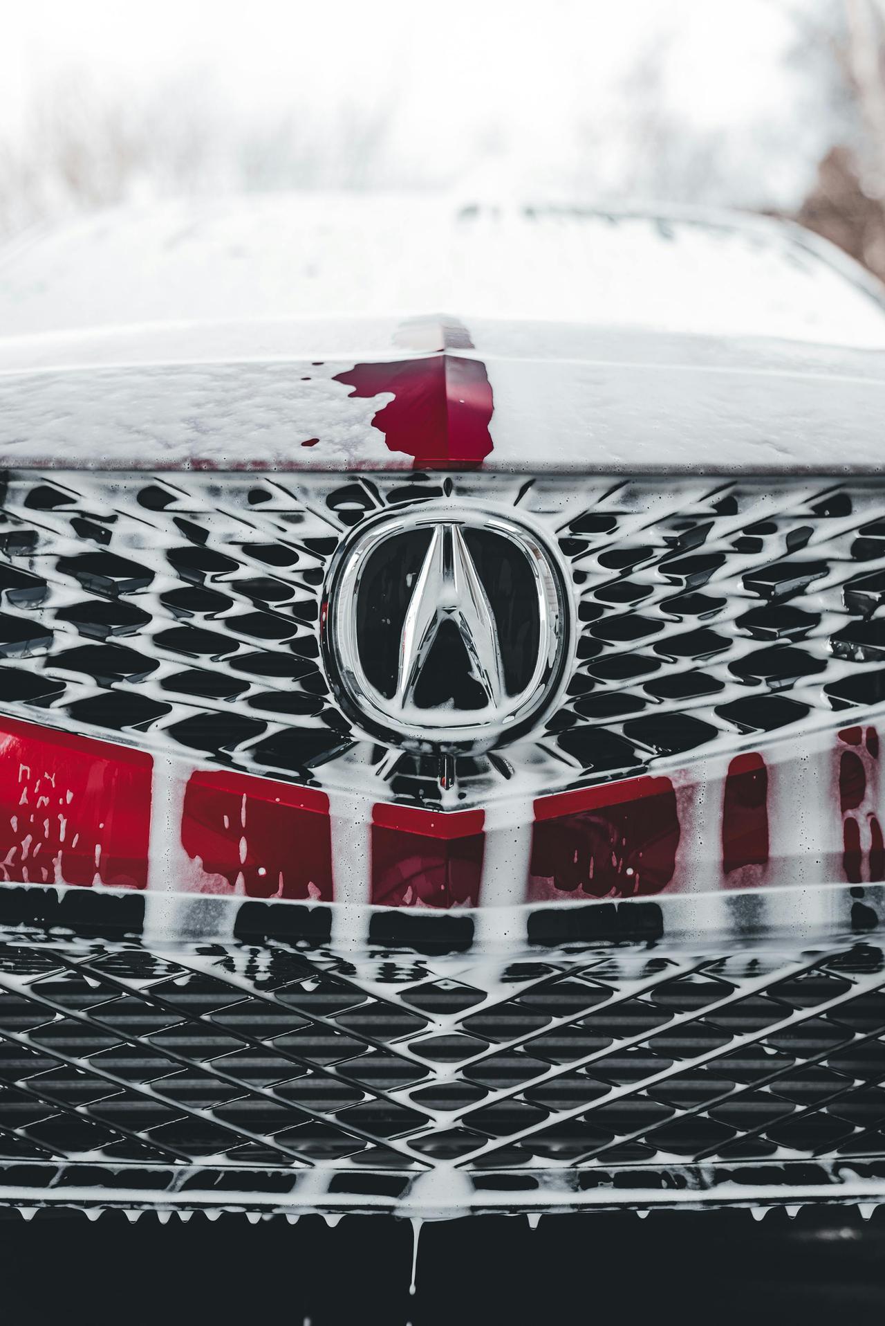 Detailed view of an Acura grille with soap suds during a car wash.
