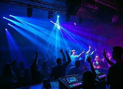 Club DJ on stage with dancing crowd and neon cyan lime lighting