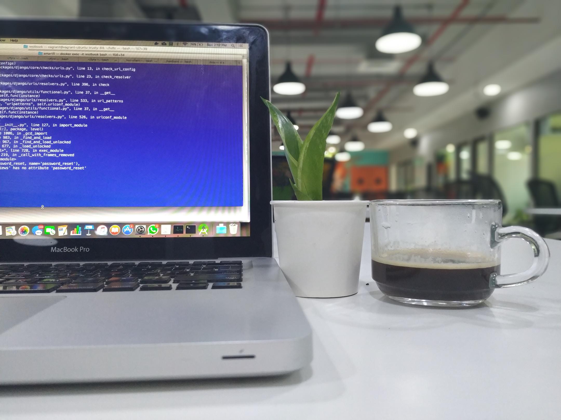 A computer, plant, and half-drunk cup of coffee on a table. An example of small business IT outsourcing services at work.