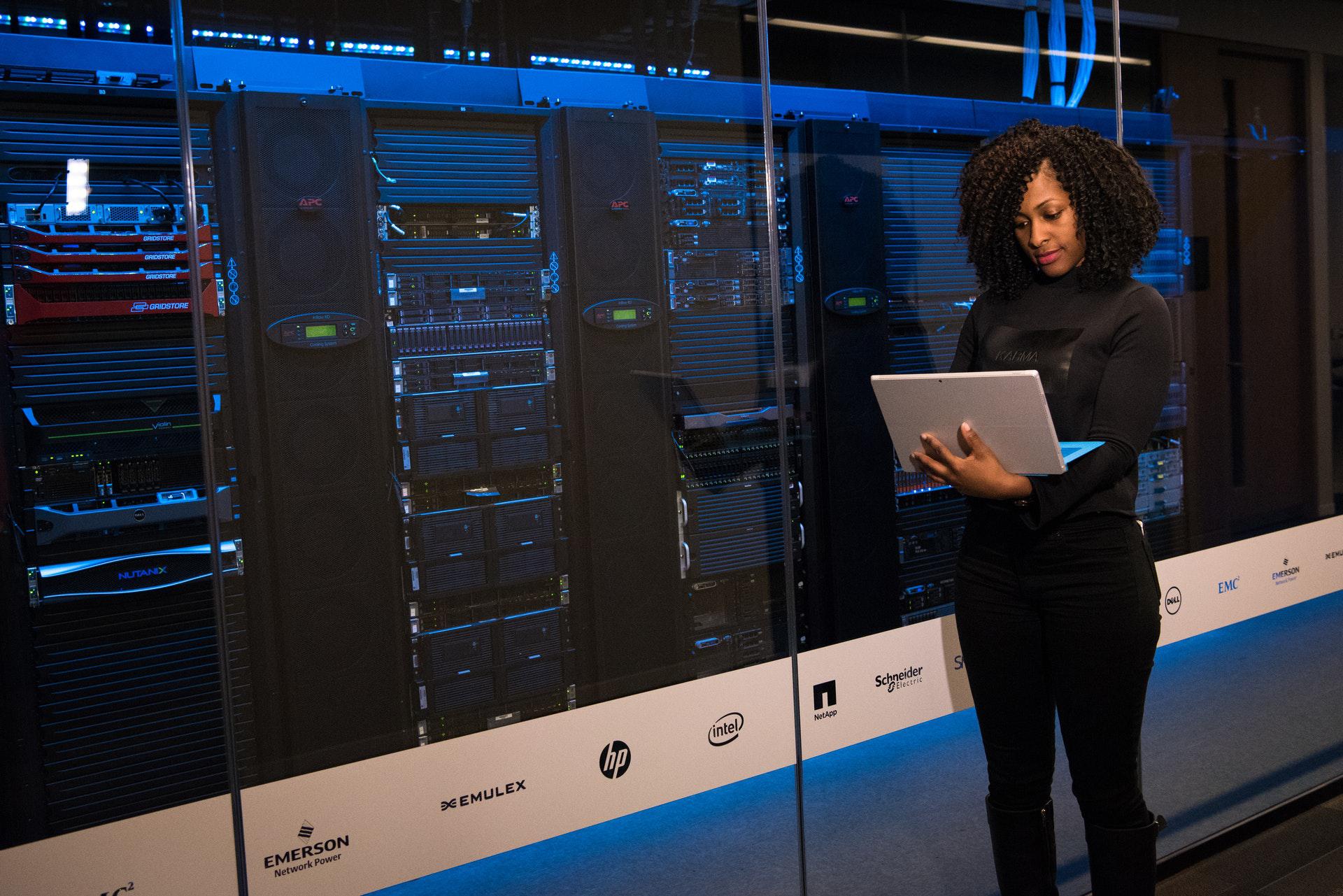 Lady with laptop beside IT system servers