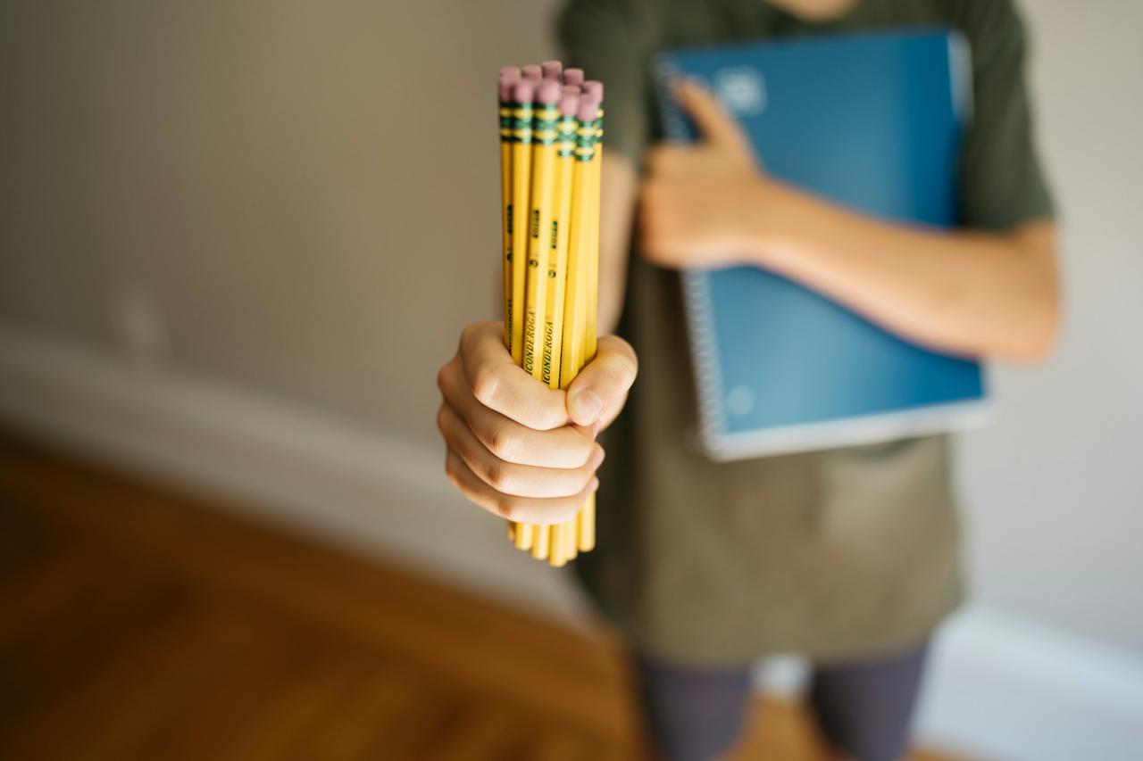 Boy holding a bundle of pencils and a notebook
