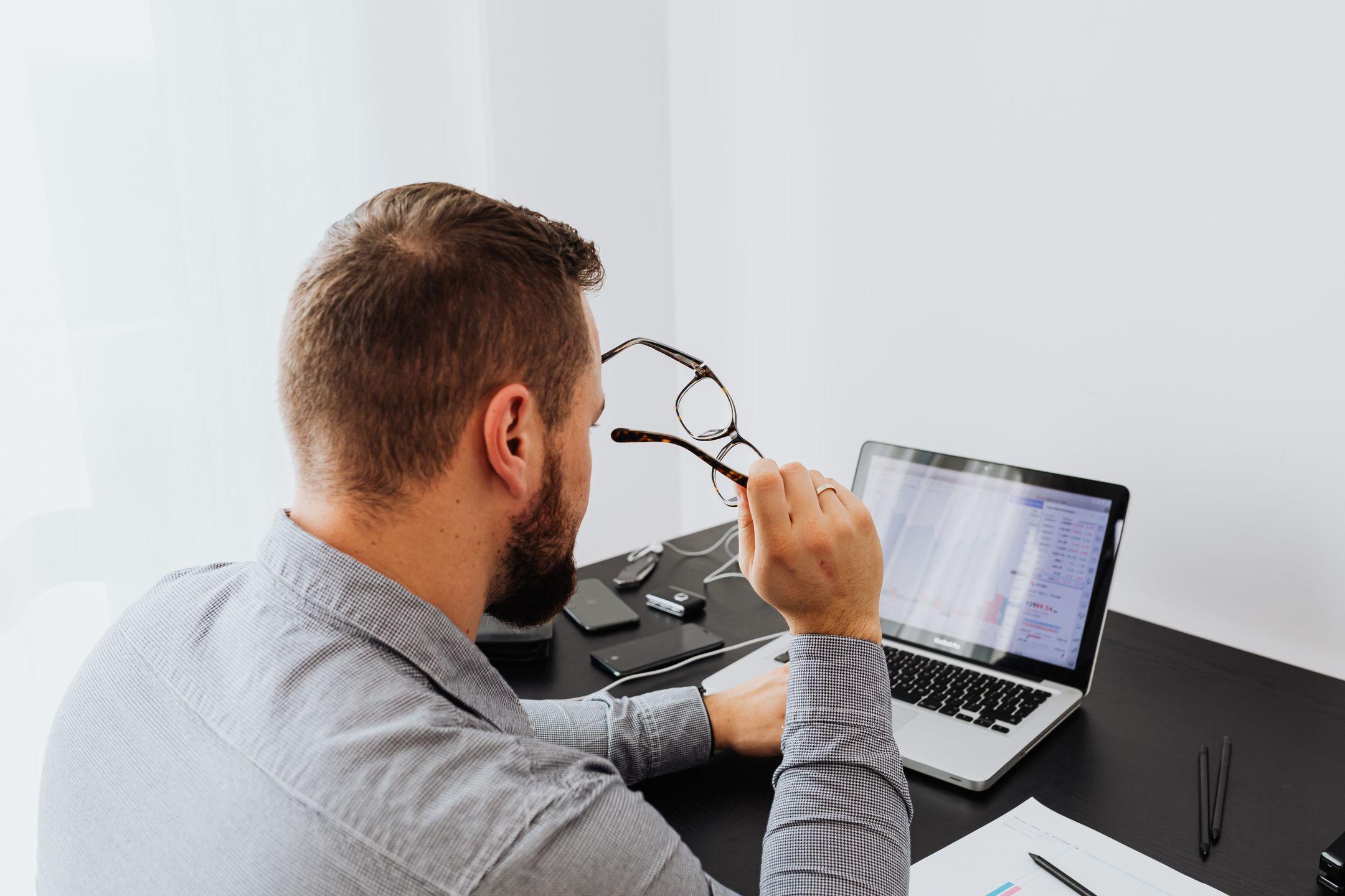 Adult man working on laptop analyzing data in modern office setting.