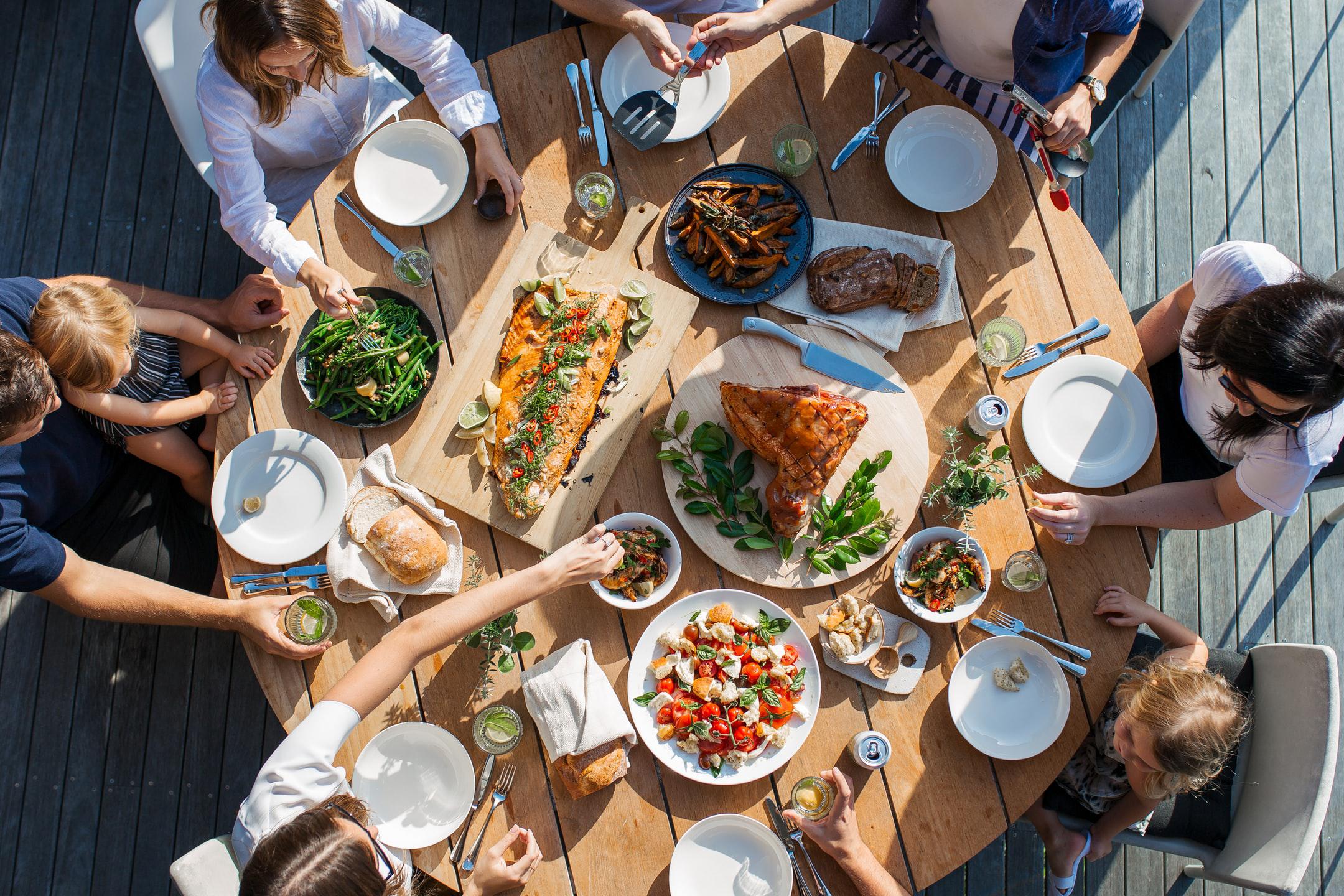 Image of a round table filled with food and surrounding by friends who worked with Dietitian For All for functional nutrition.