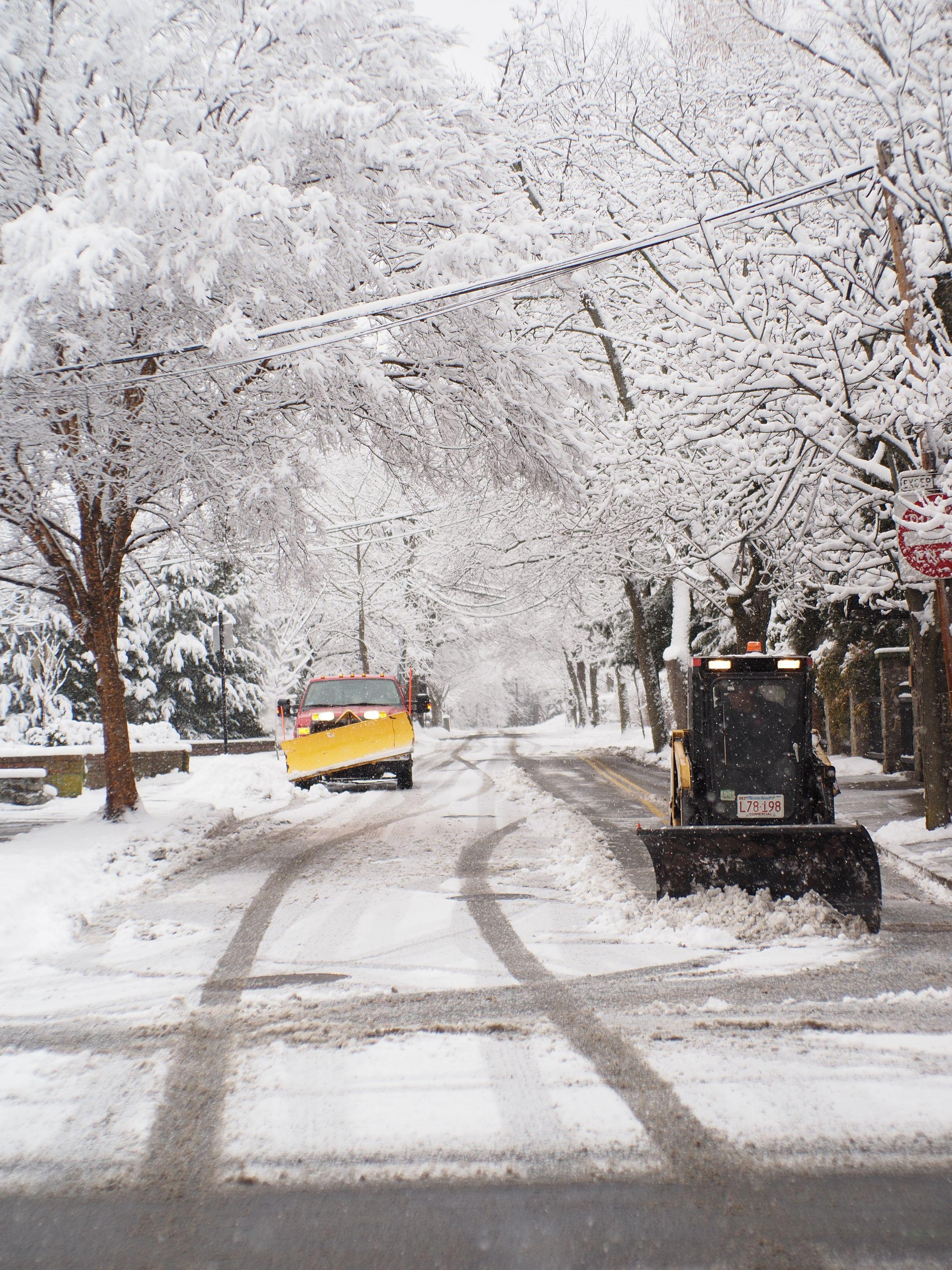 Snowplows clear a snowy street in Boston, showcasing winter's beauty and challenges.