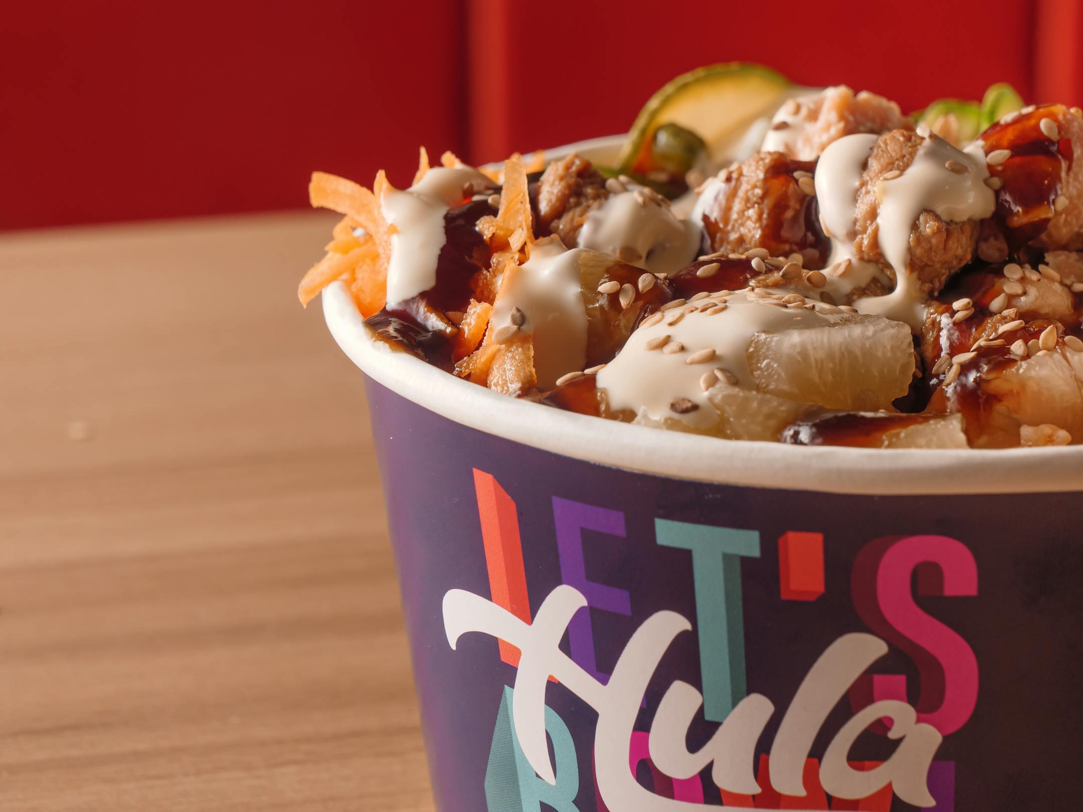 Delicious Hawaiian poke bowl in a colorful paper container, rich in flavors and textures.