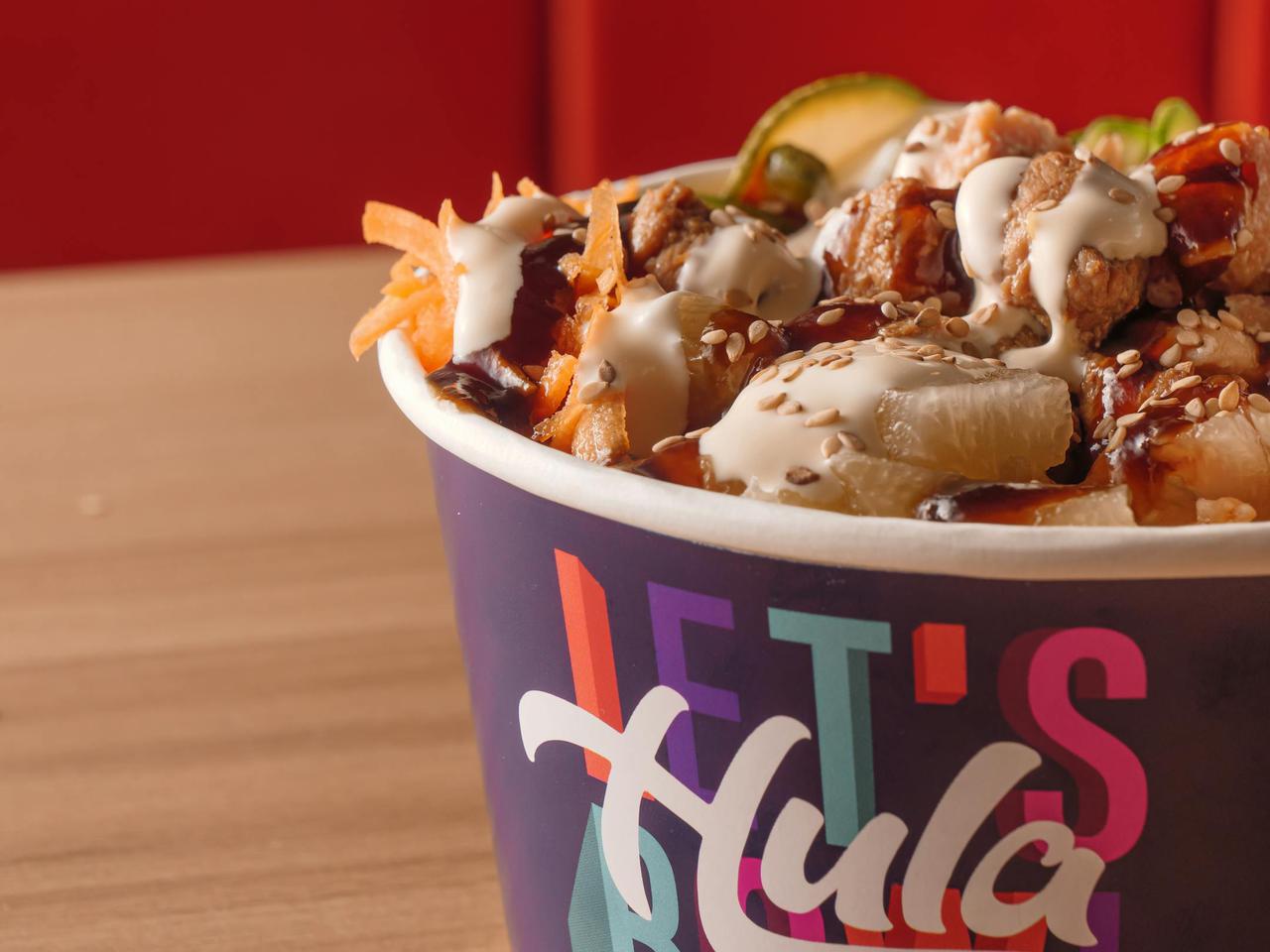 Delicious Hawaiian poke bowl in a colorful paper container, rich in flavors and textures.