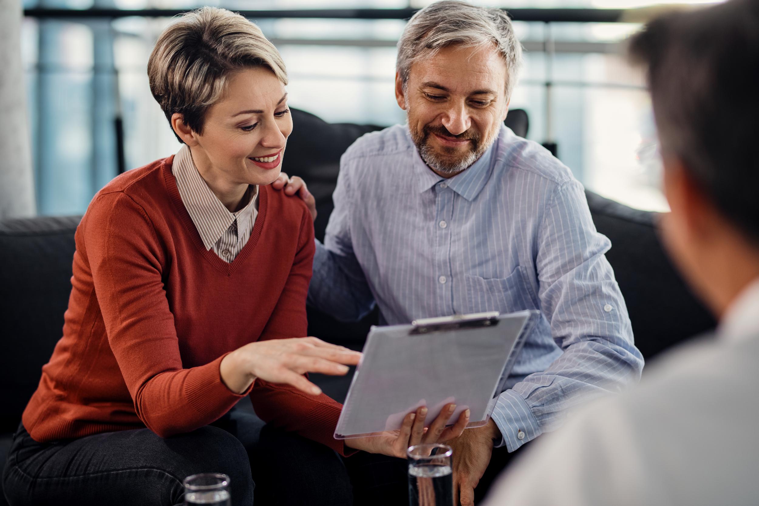 happy-couple-going-through-terms-agreement-during-meeting-with-financial-advisor.jpg
