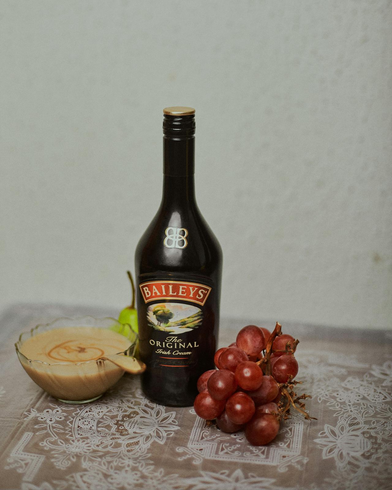 Port Harcourt | Nigeria - 9th April 2021: Flatlay with a bottle of Baileys wine, a bowl of pap and red grapes on a table.
