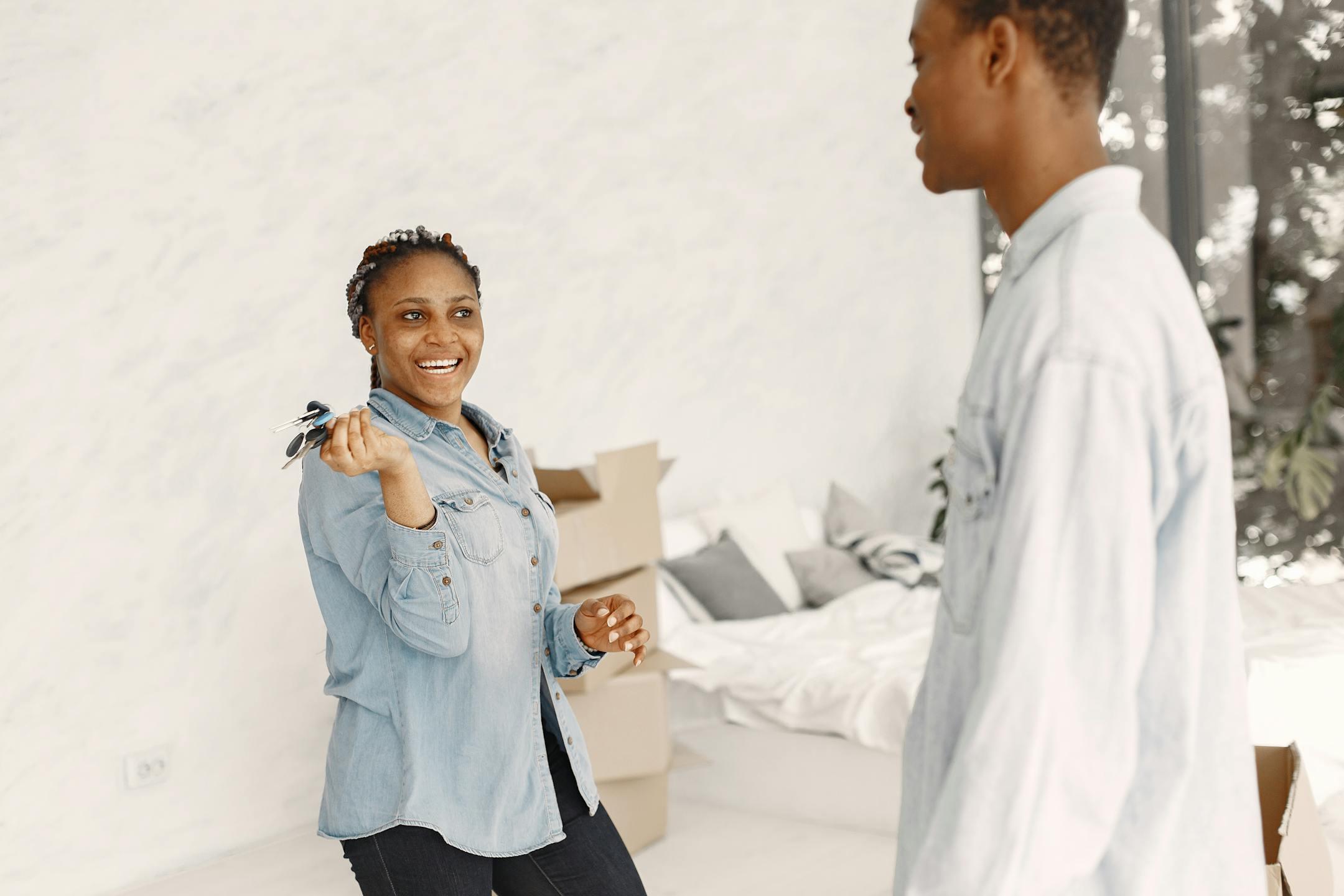 Smiling couple indoors holding keys, moving into a new home.
