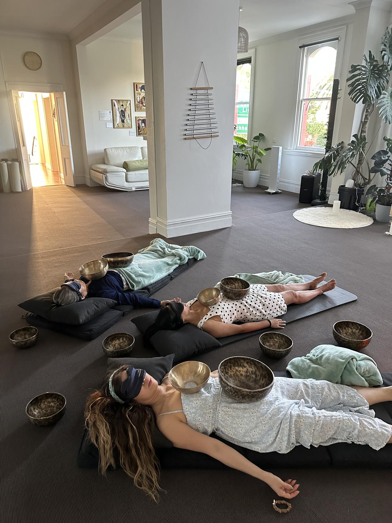 People lying down with sound bowls during healing session