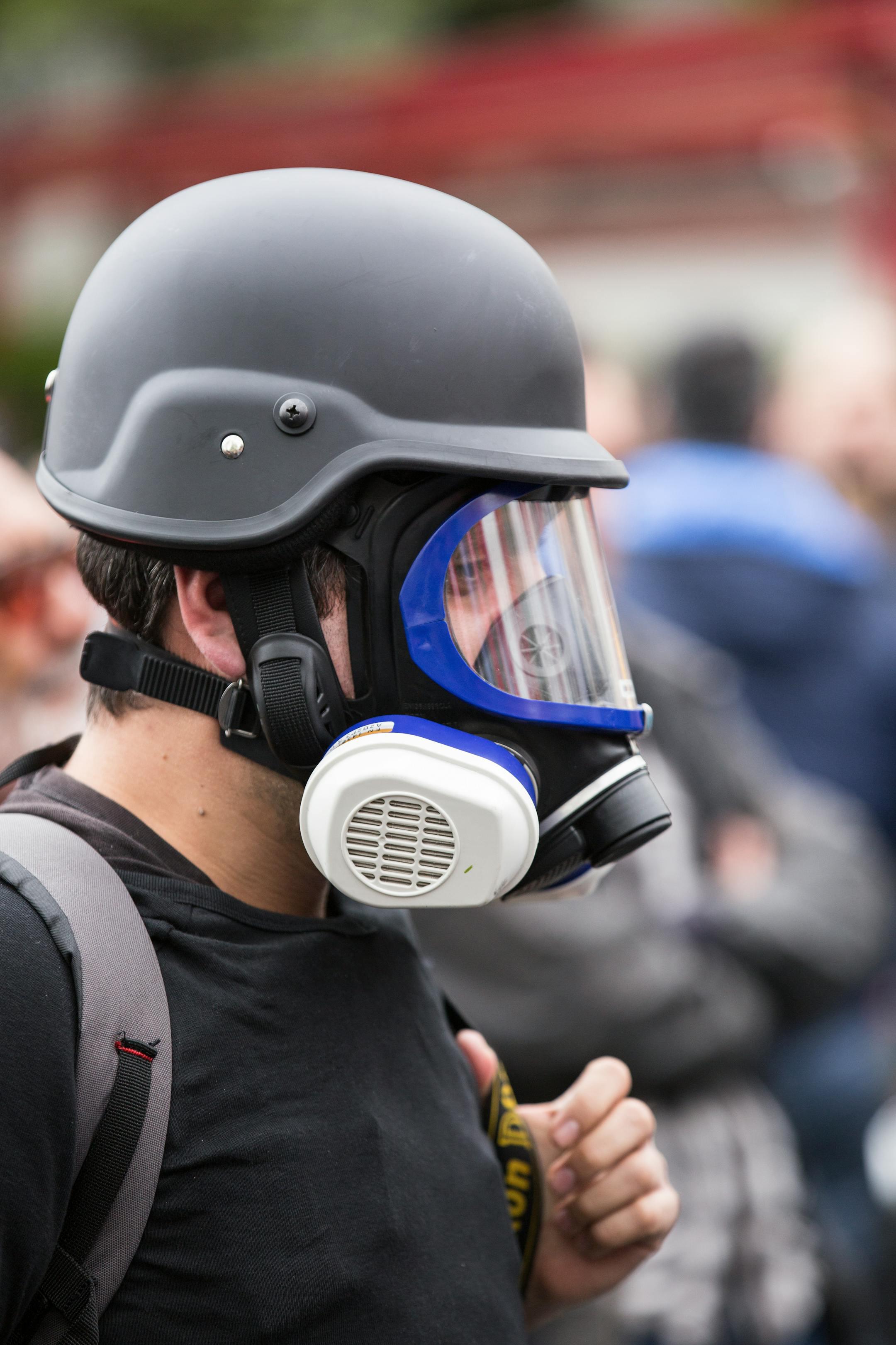 Close-up of a person in protective gear including gas mask and helmet.