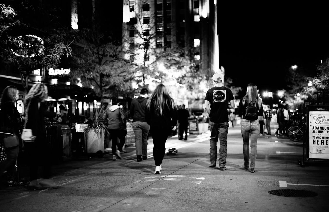 A black and white city scene featuring people walking at night, capturing urban lifestyle energy.