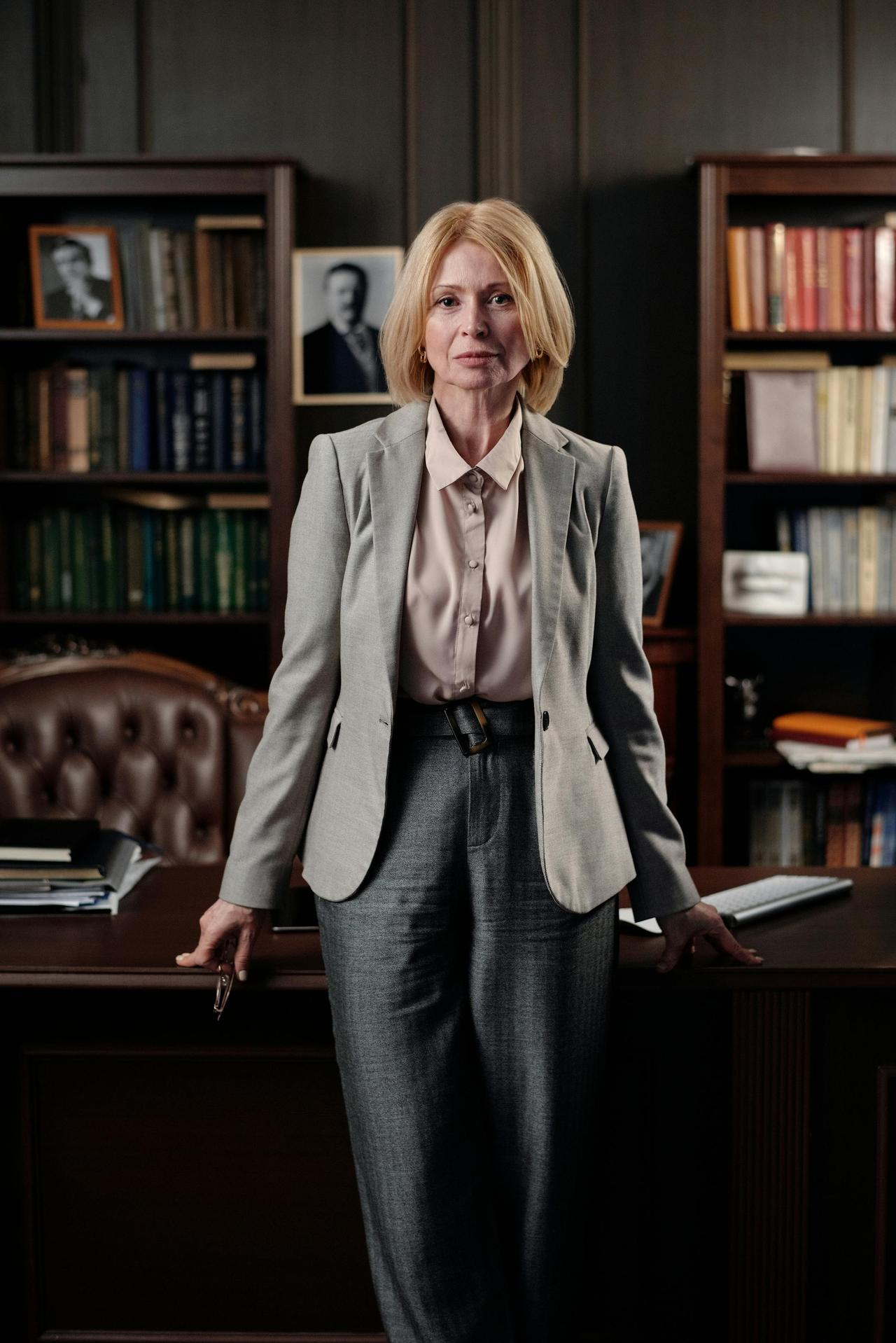 Professional businesswoman standing confidently in a classic office, exuding leadership and success.