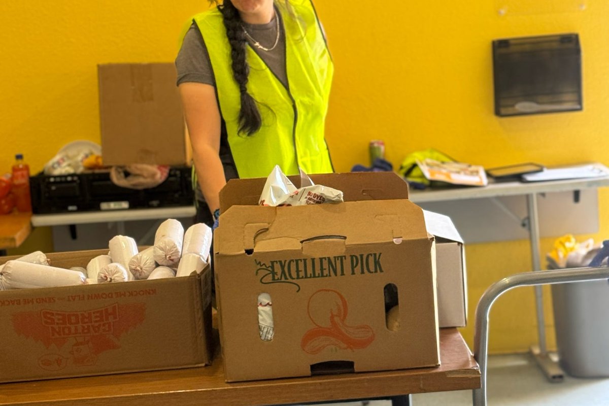 A participant in a safety vest sorting produce into boxes.